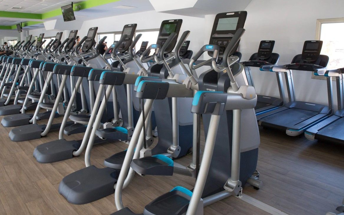 Una fila de cintas de correr y elípticas en un gimnasio.