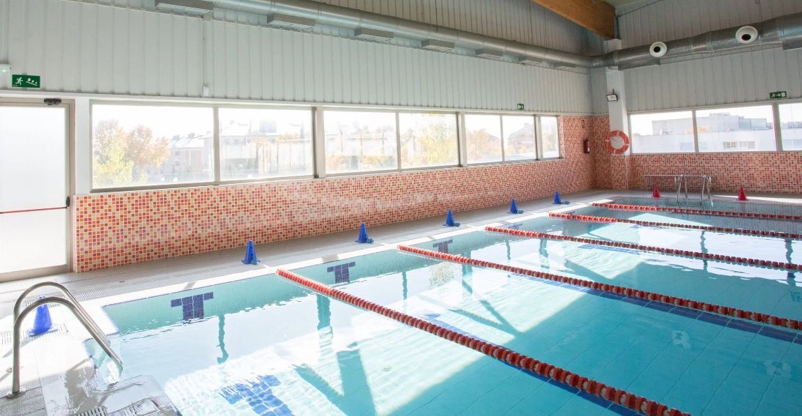 Hay una gran piscina cubierta con muchas ventanas.