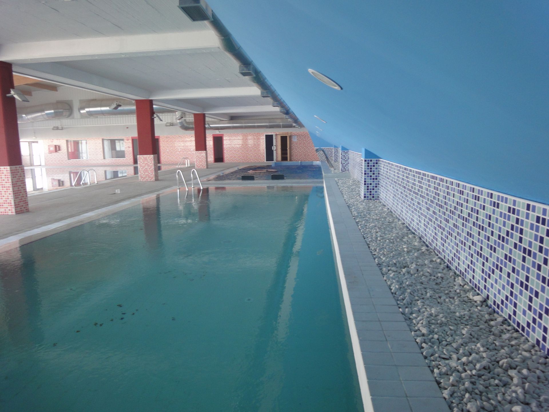 Una gran piscina cubierta con una pared azul