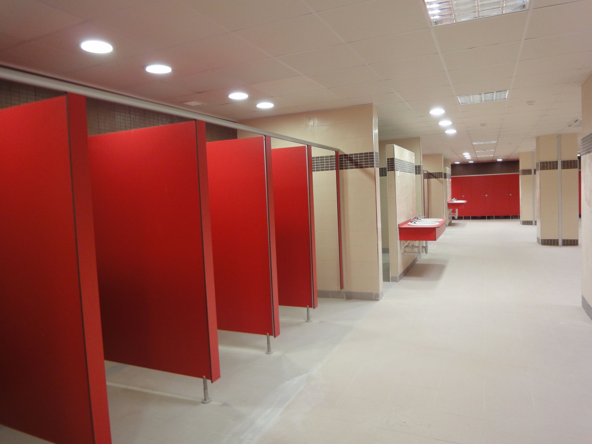 Un pasillo con divisores rojos y lavabos en un baño público.