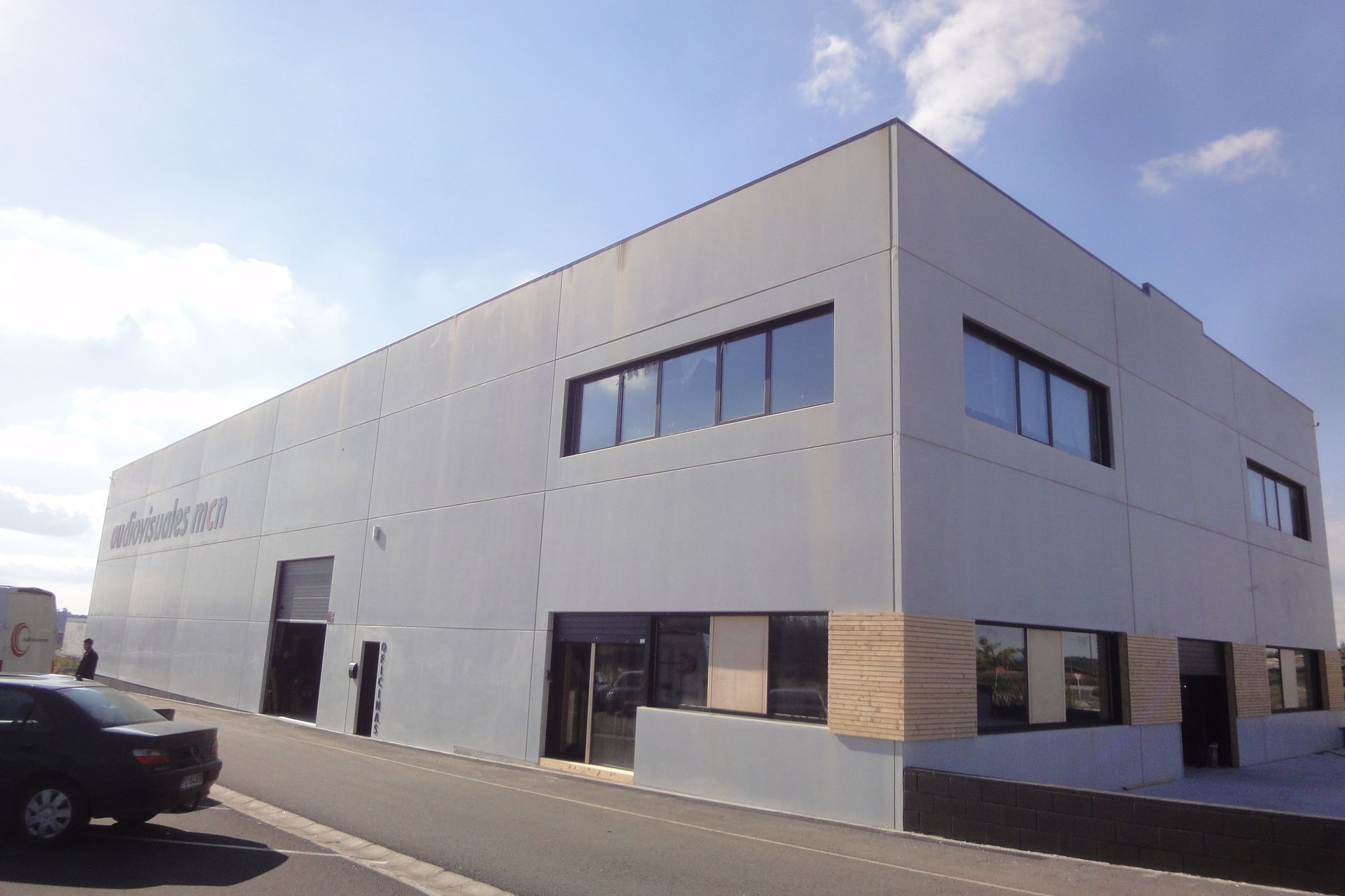 Un gran edificio blanco con un coche aparcado delante.