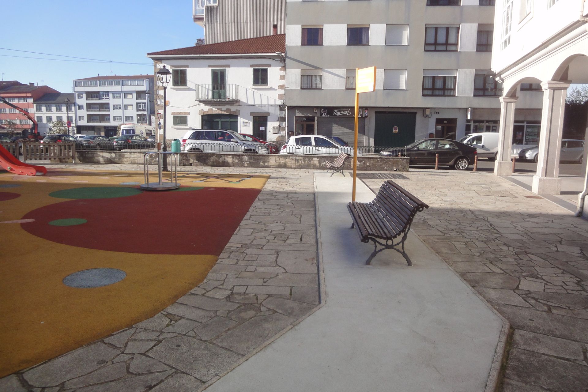 Un parque con un banco y un tobogán al fondo.