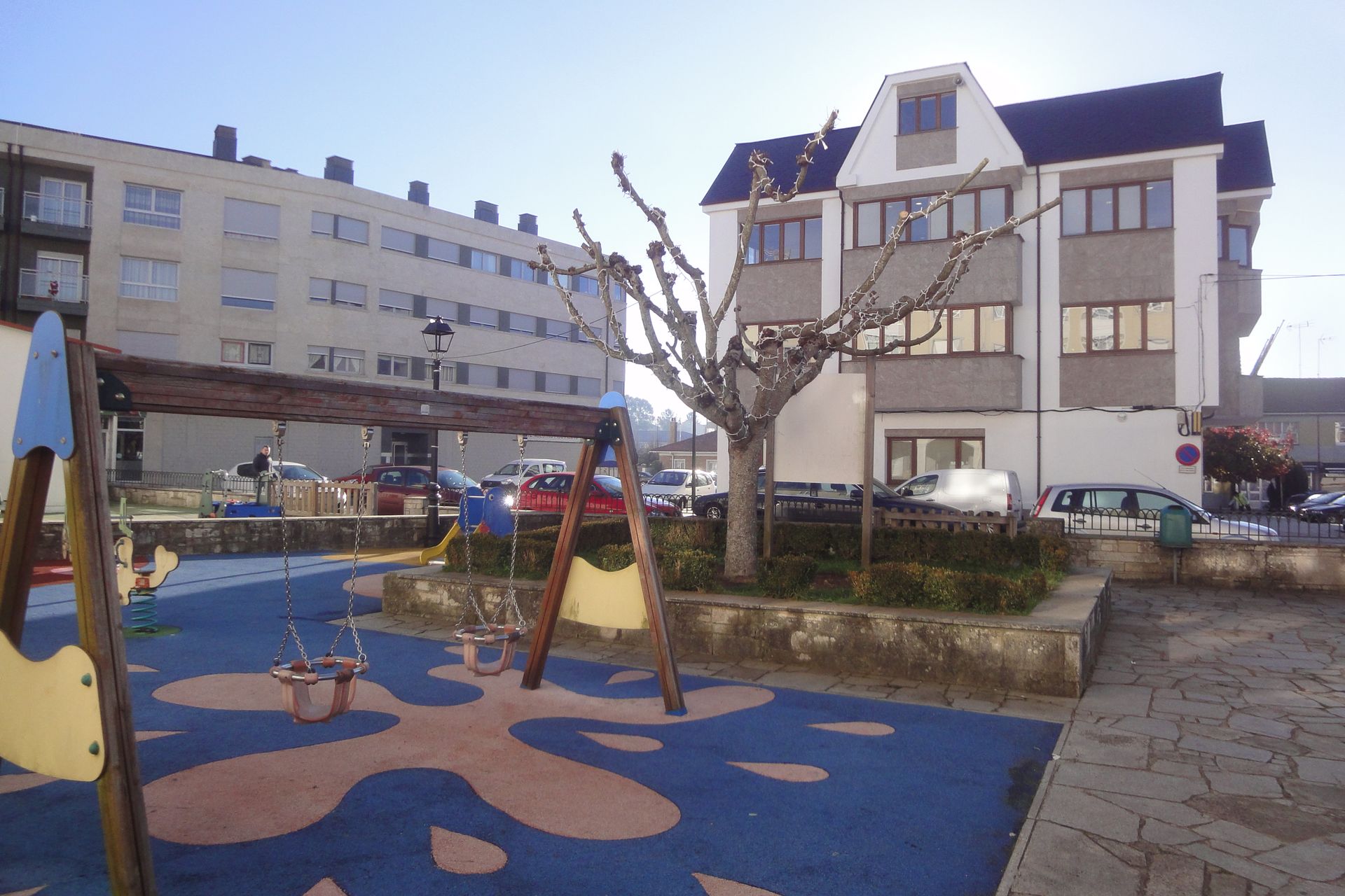 Un parque infantil con columpios frente a un edificio.