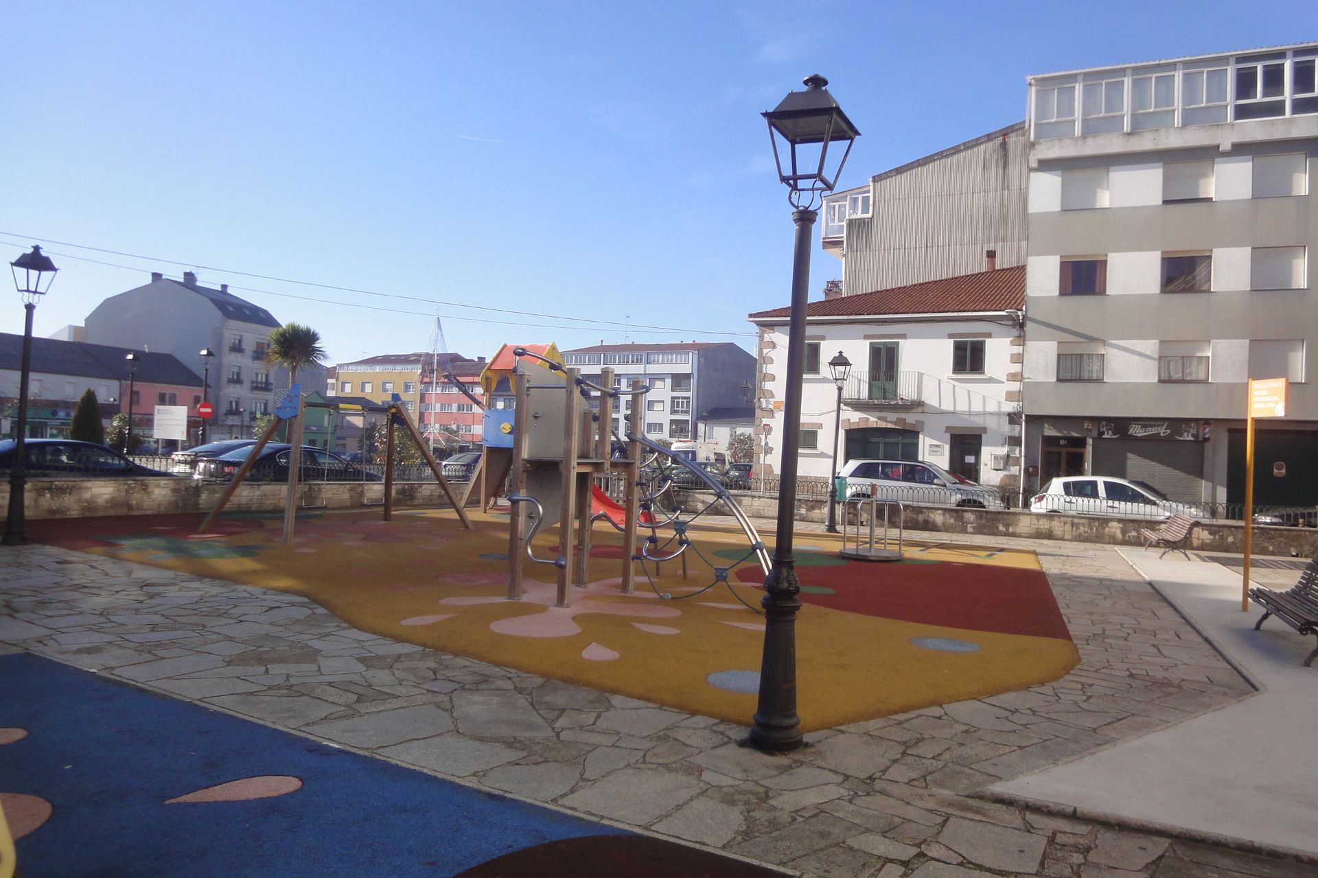 Un parque con una zona de juegos infantiles en medio de una ciudad.