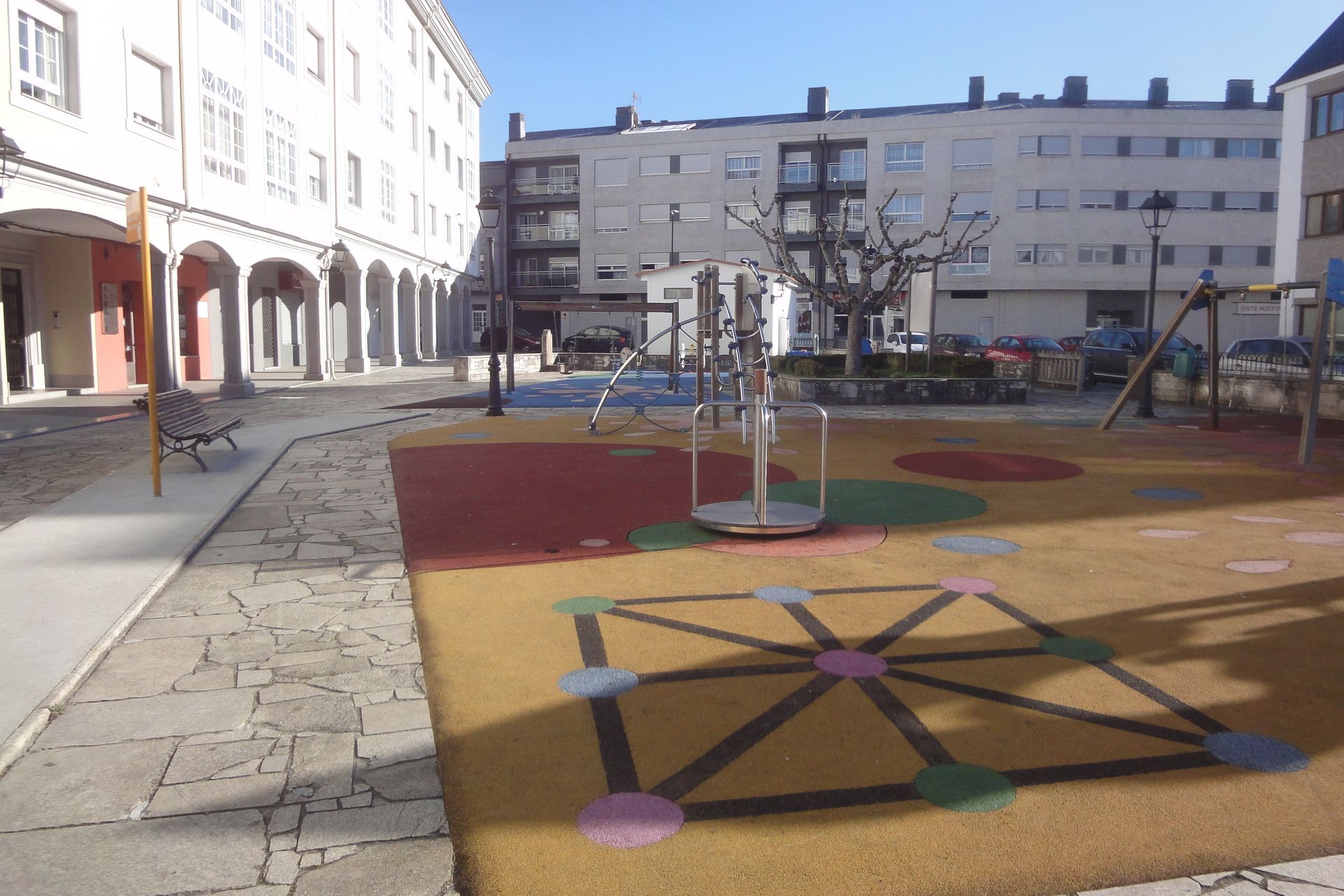 Un parque infantil con un columpio y un patrón geométrico en el suelo.