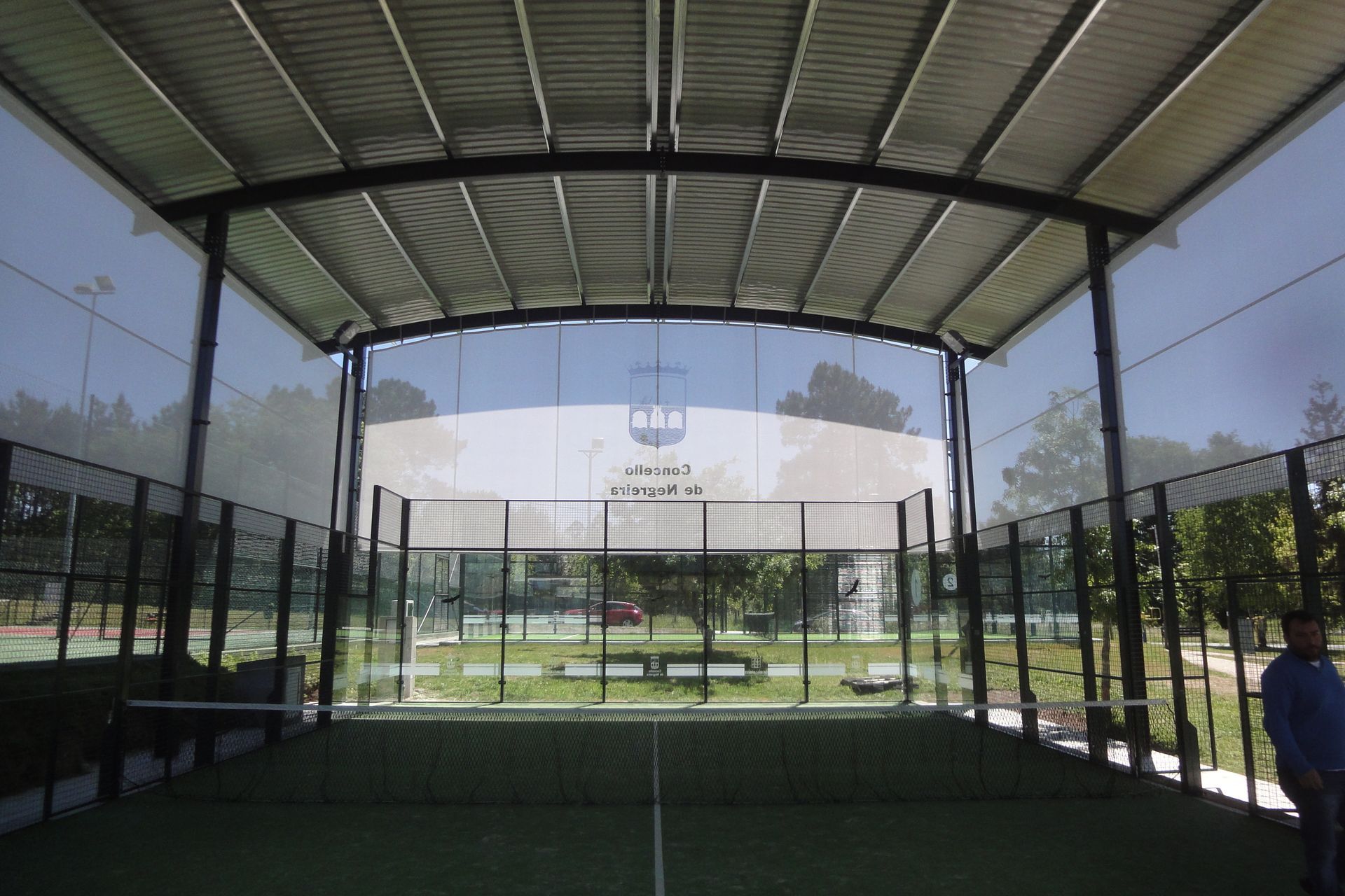 Una vista de una pista de pádel desde el interior de un edificio.