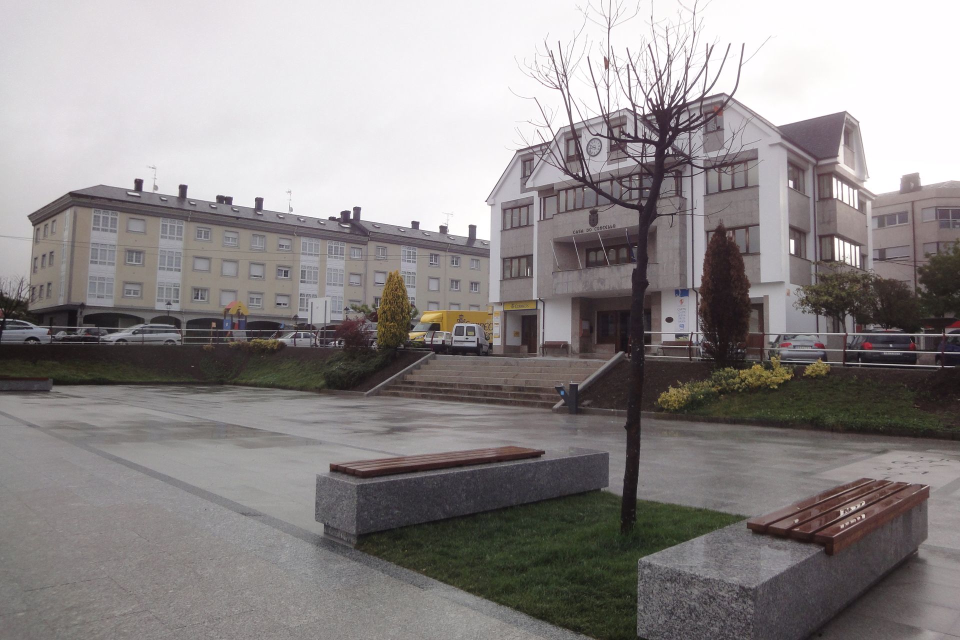 Un parque con un árbol y bancos frente a un edificio.