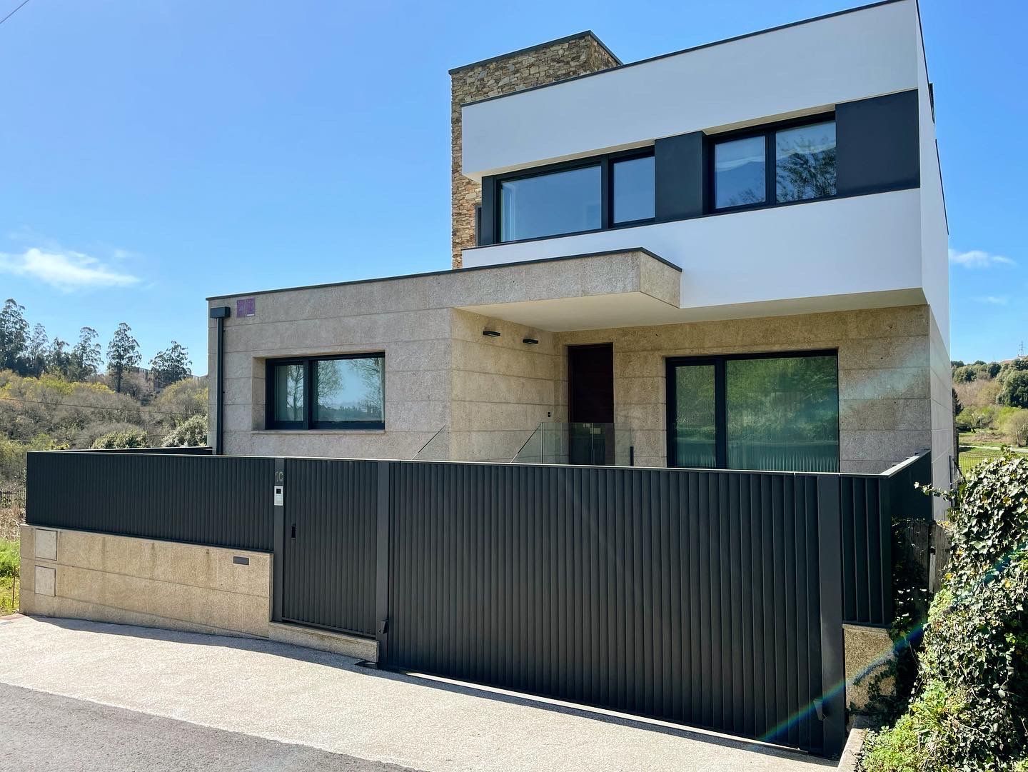 Una casa moderna con una valla negra delante.