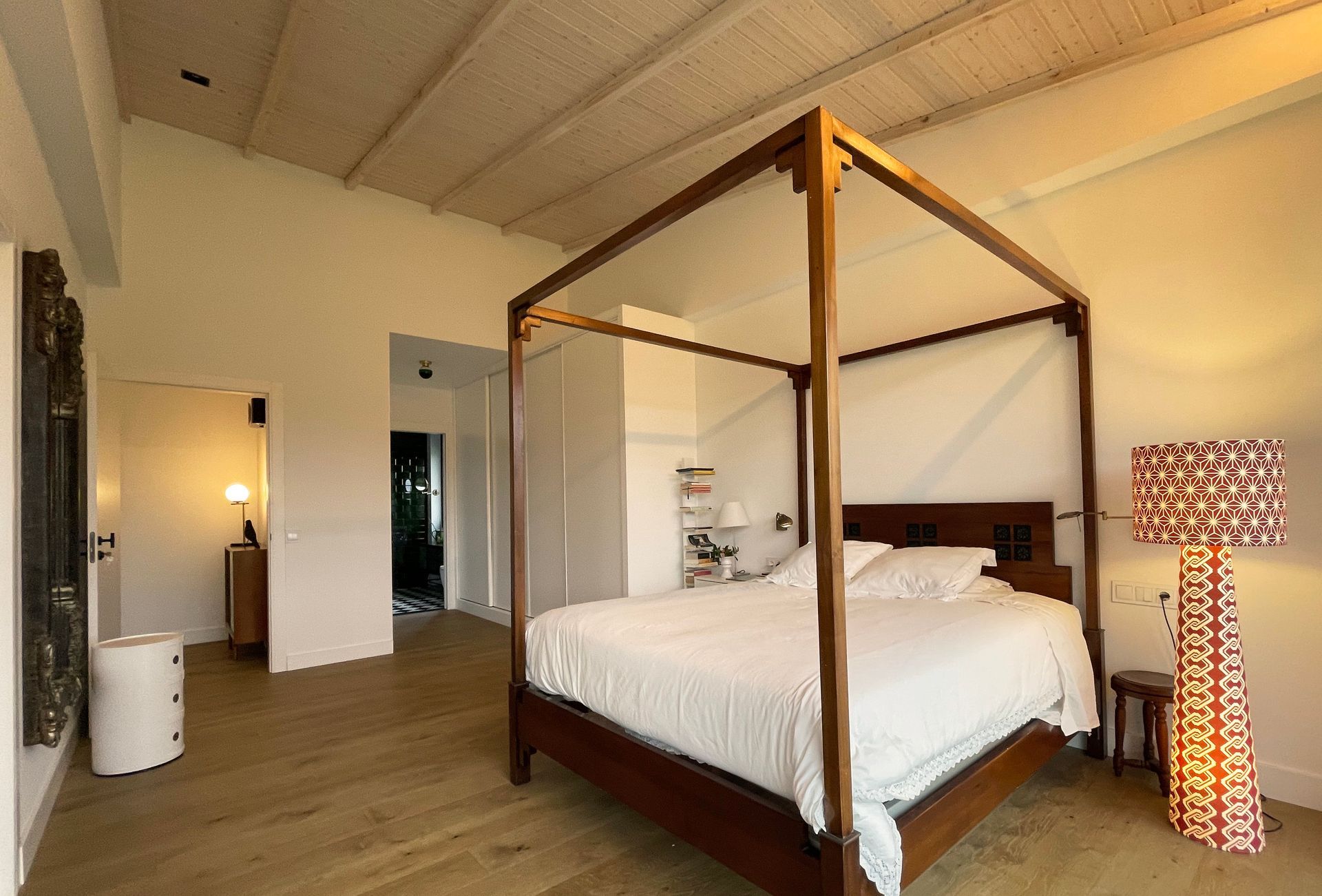 Un dormitorio con una cama con dosel y una lámpara.