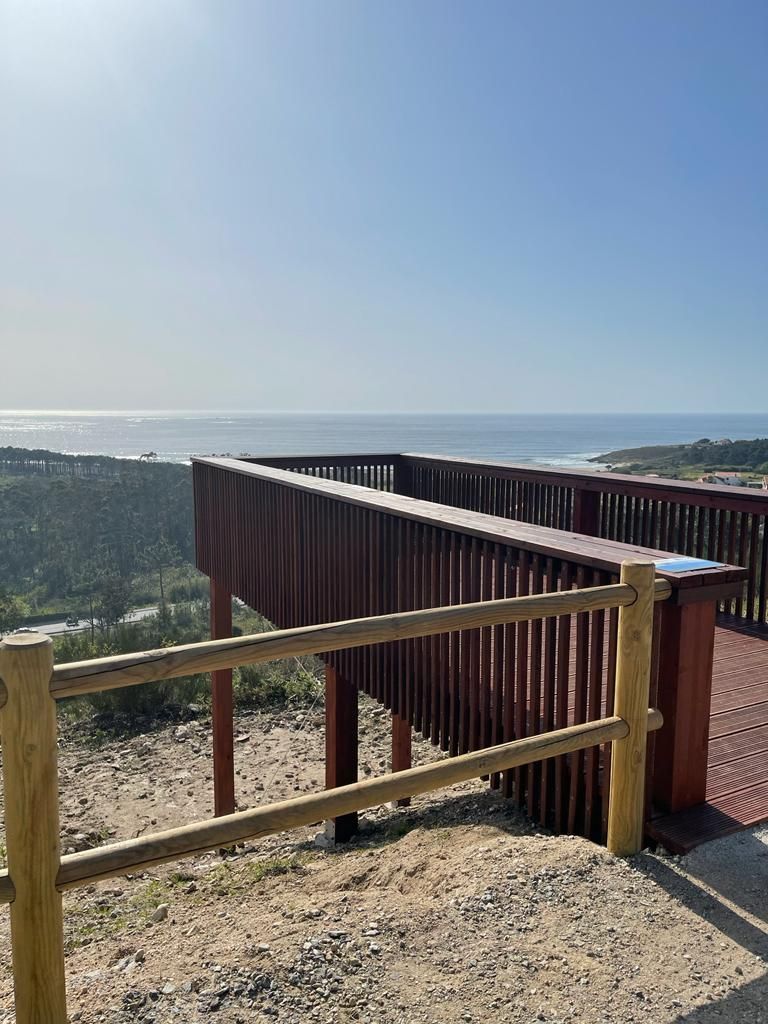 Una valla de madera rodea una terraza de madera con vistas al océano.