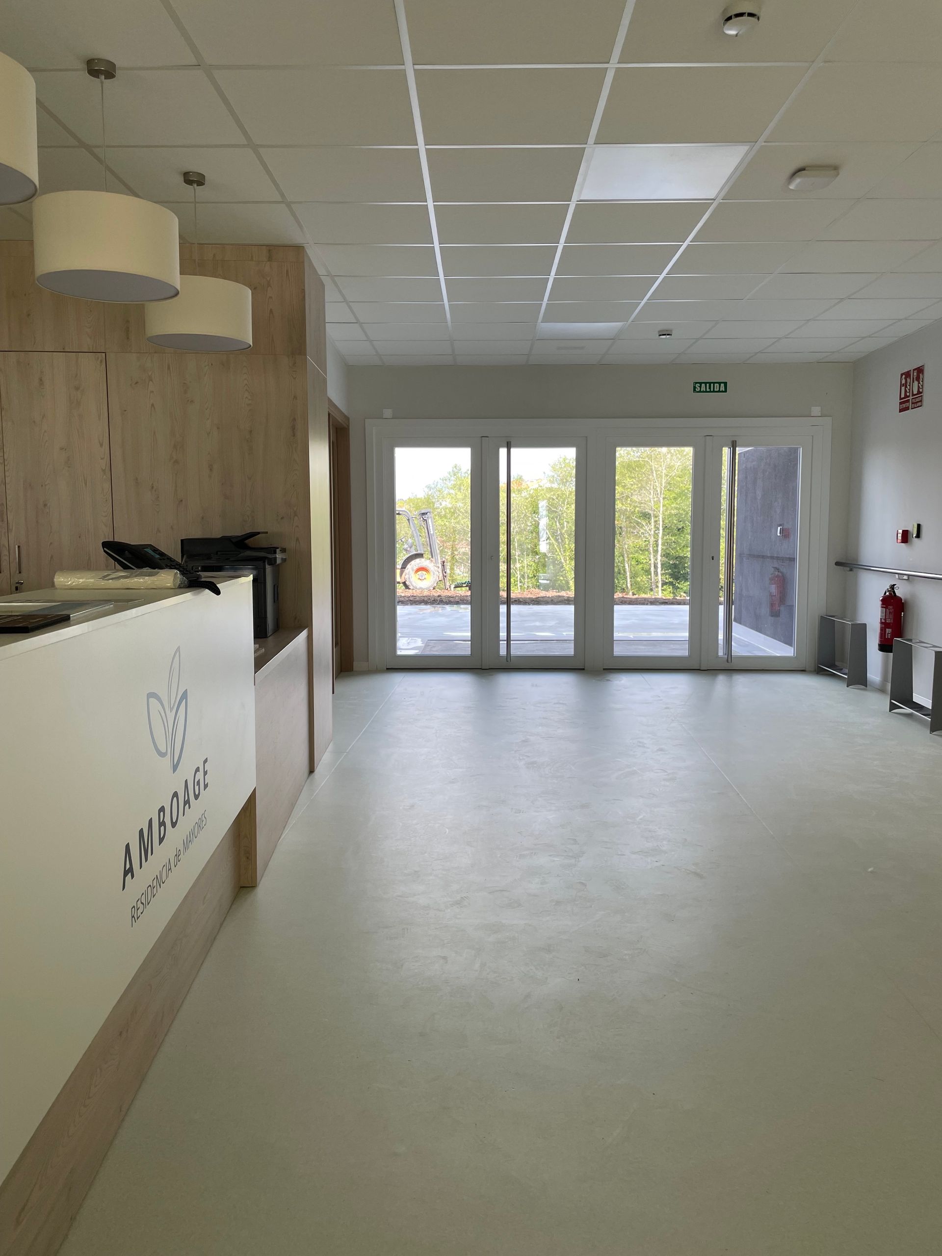 Una gran sala vacía con un mostrador de recepción y un extintor de incendios.