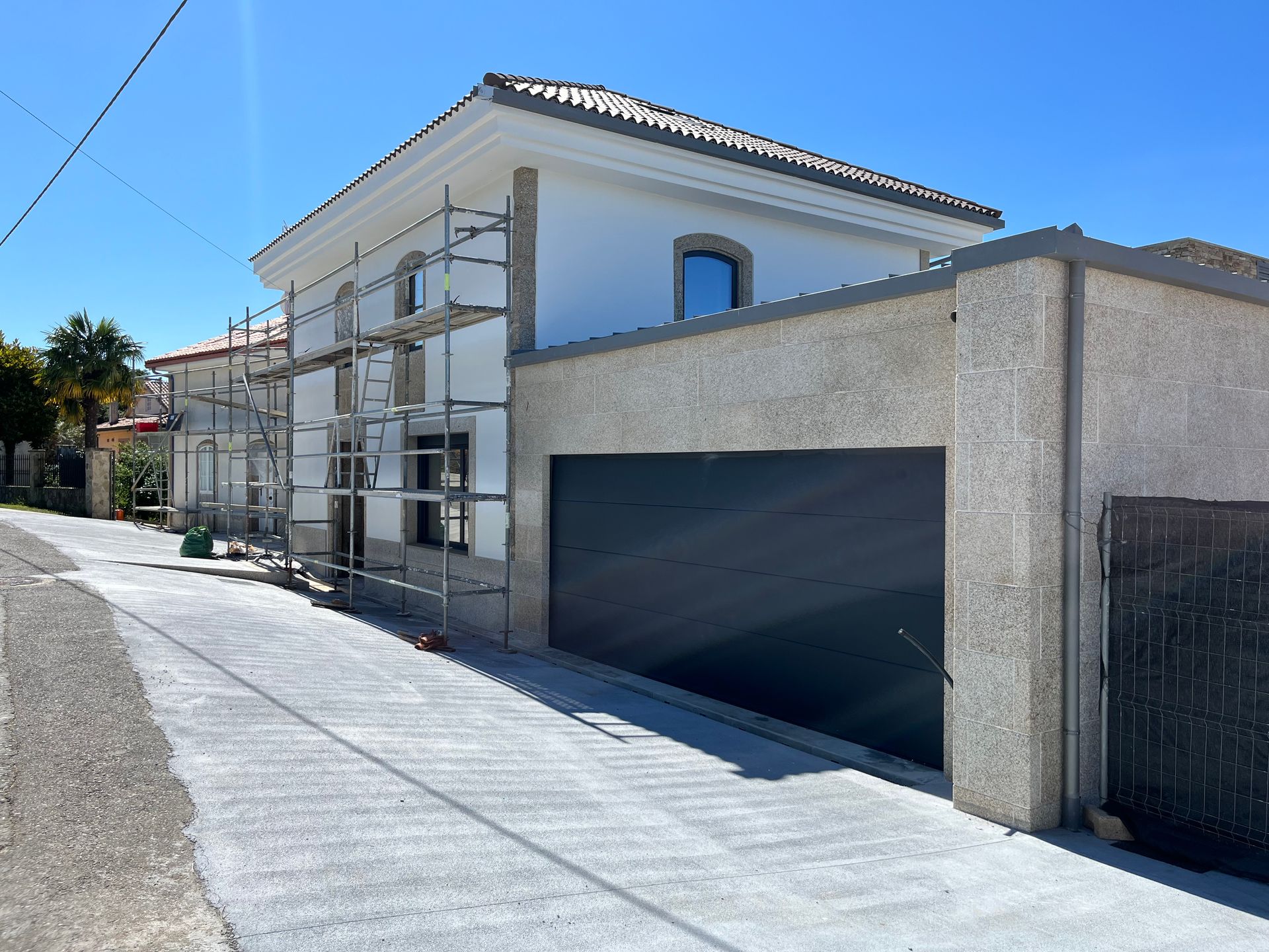 Una casa blanca con andamios alrededor y una puerta de garaje negra.