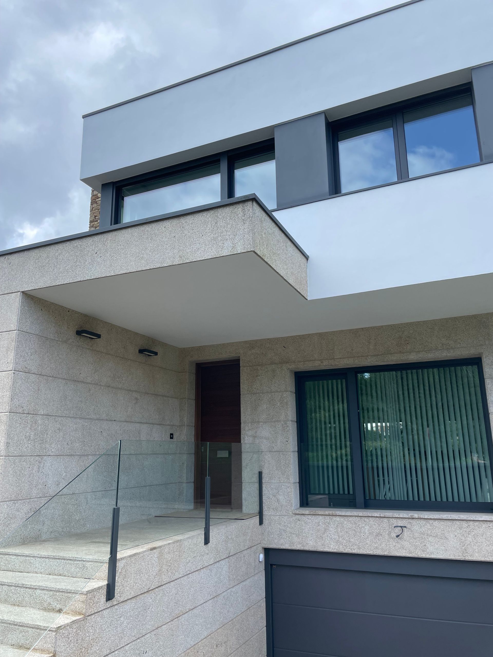 El frente de una casa con balcón y escaleras.