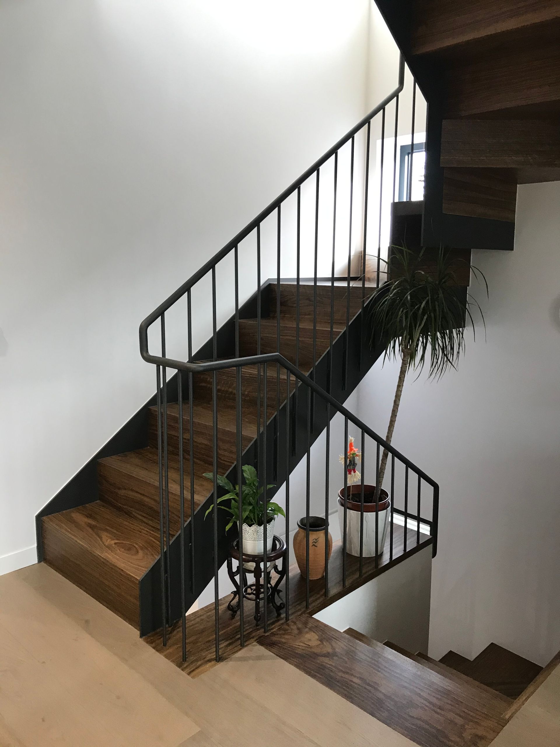 Una escalera de madera con barandilla de metal y plantas en macetas en los escalones.