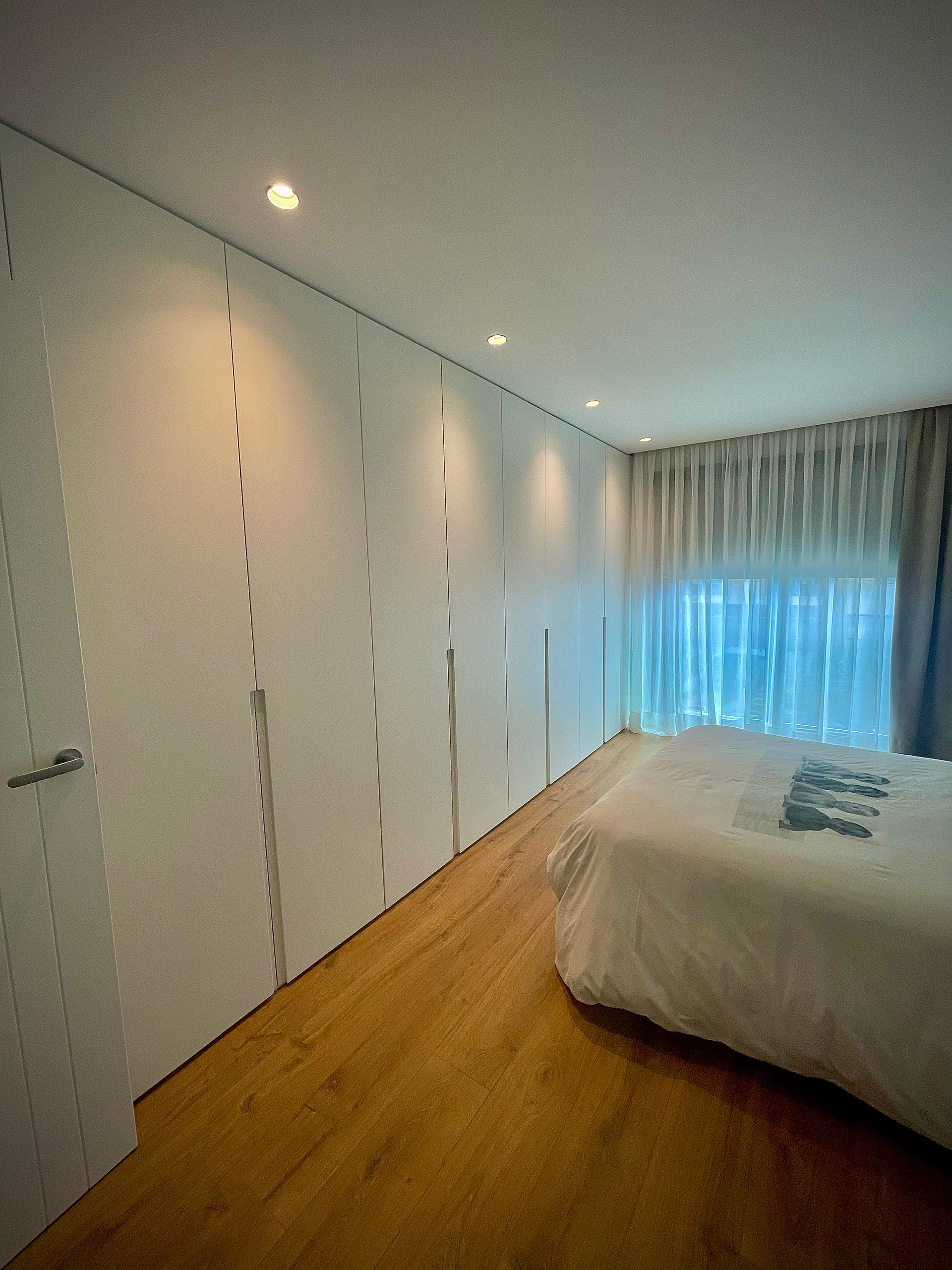 Un dormitorio con una cama y muchas puertas blancas.