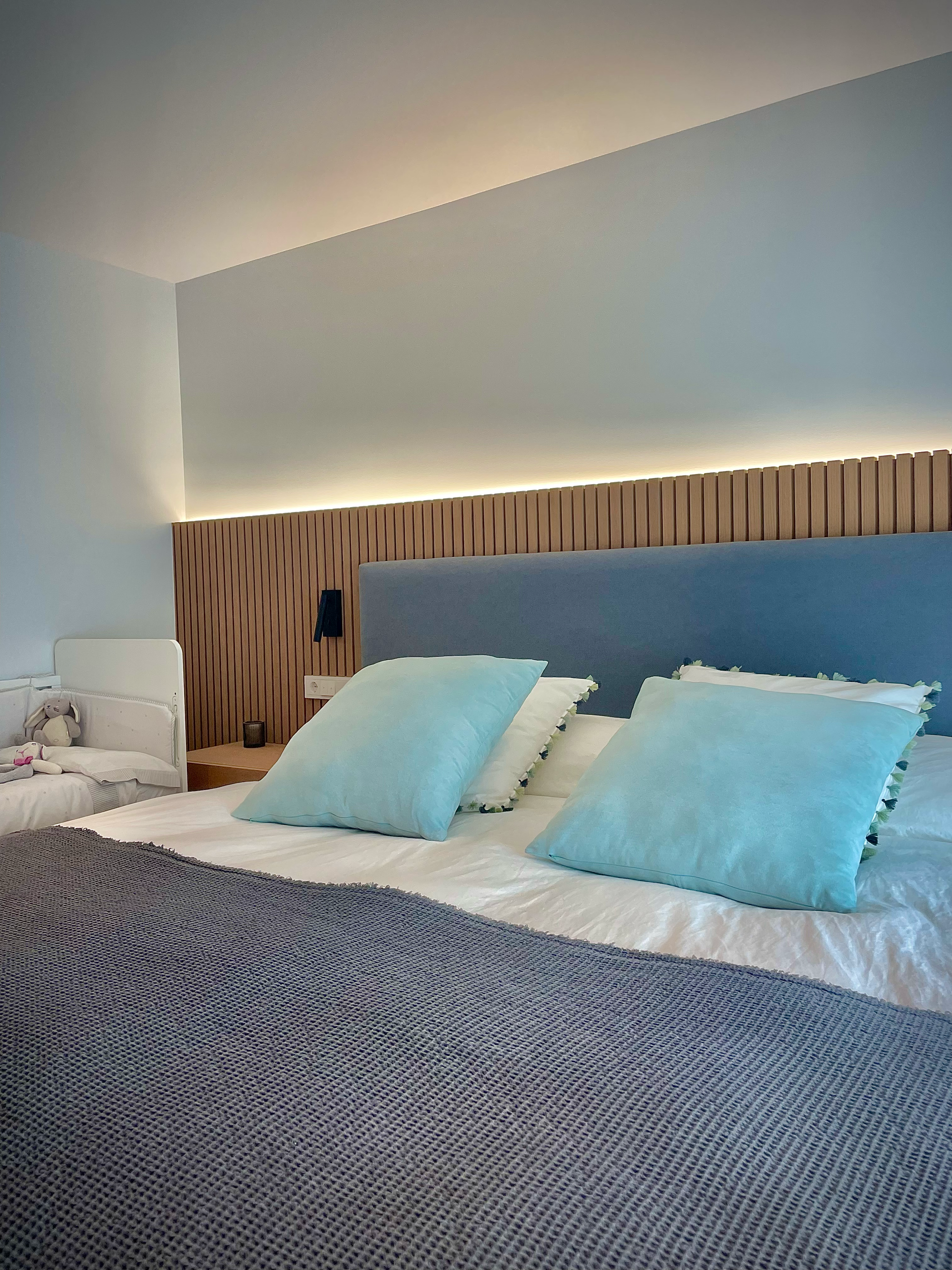Una cama con almohadas azules y un cabecero azul en un dormitorio.