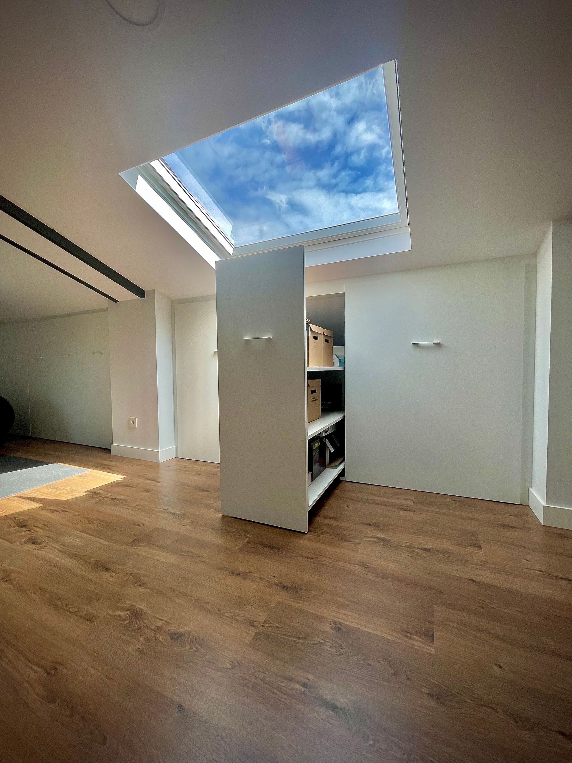 Una habitación con pisos de madera y un tragaluz en el techo.