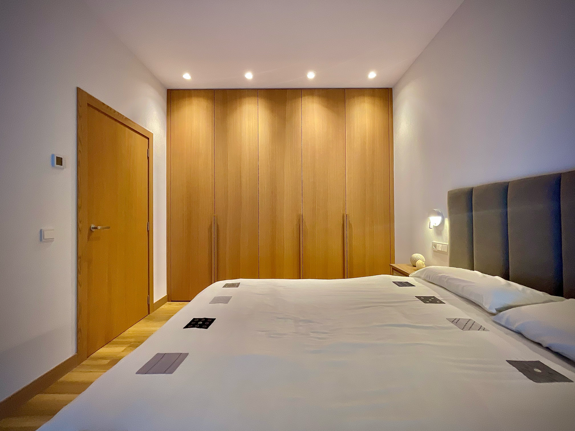 Un dormitorio con una cama, armarios y una puerta.