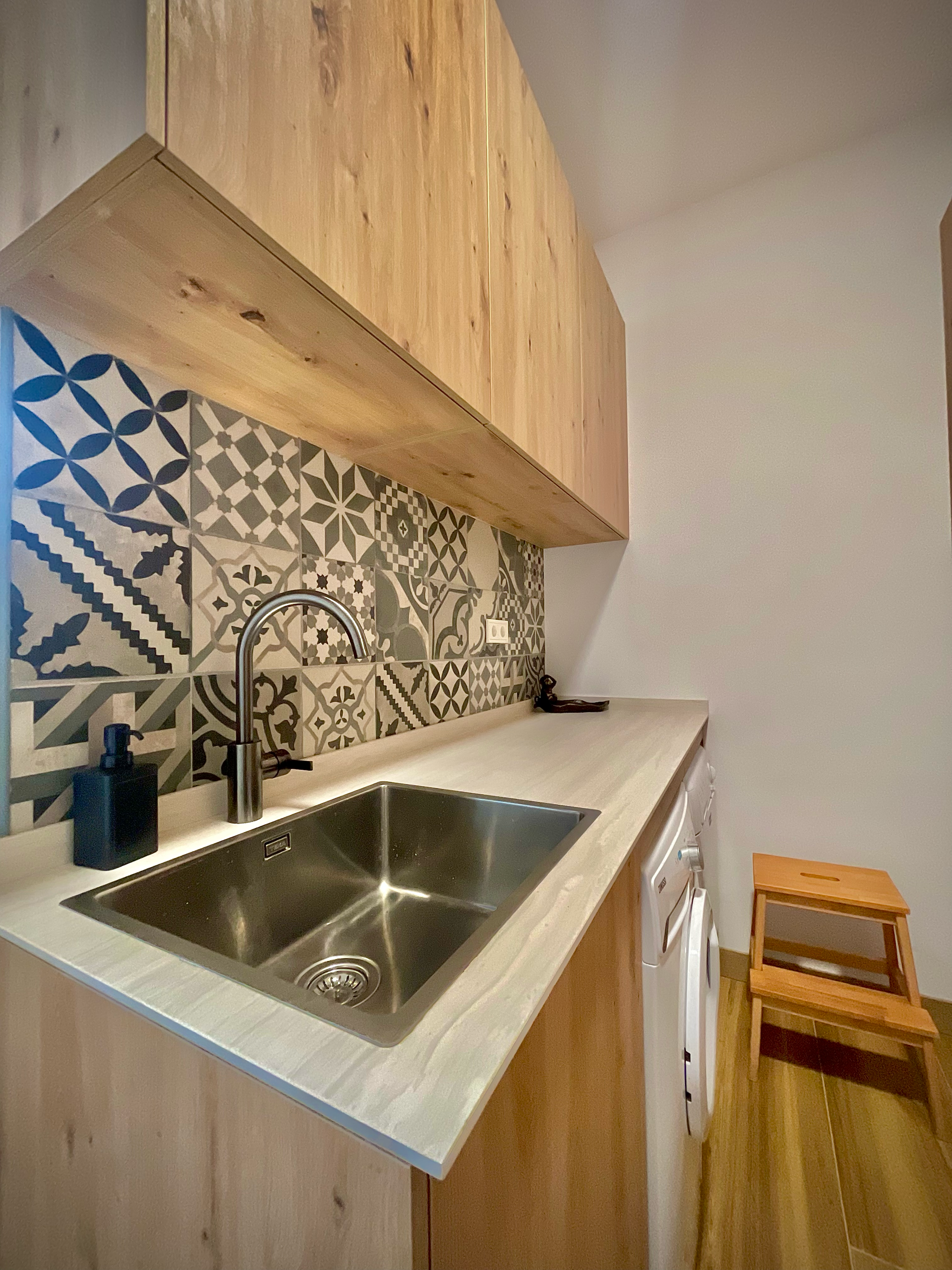 Una cocina con fregadero de acero inoxidable y gabinetes de madera.