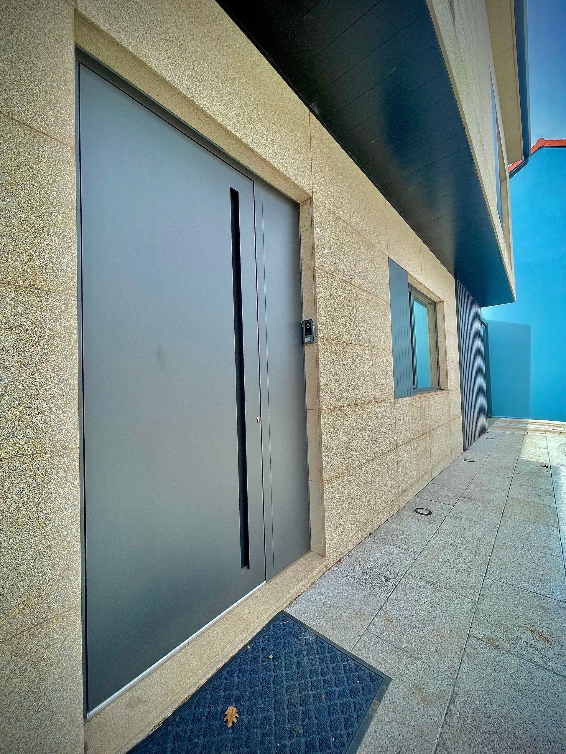 Un edificio con una puerta y una estera delante de él.