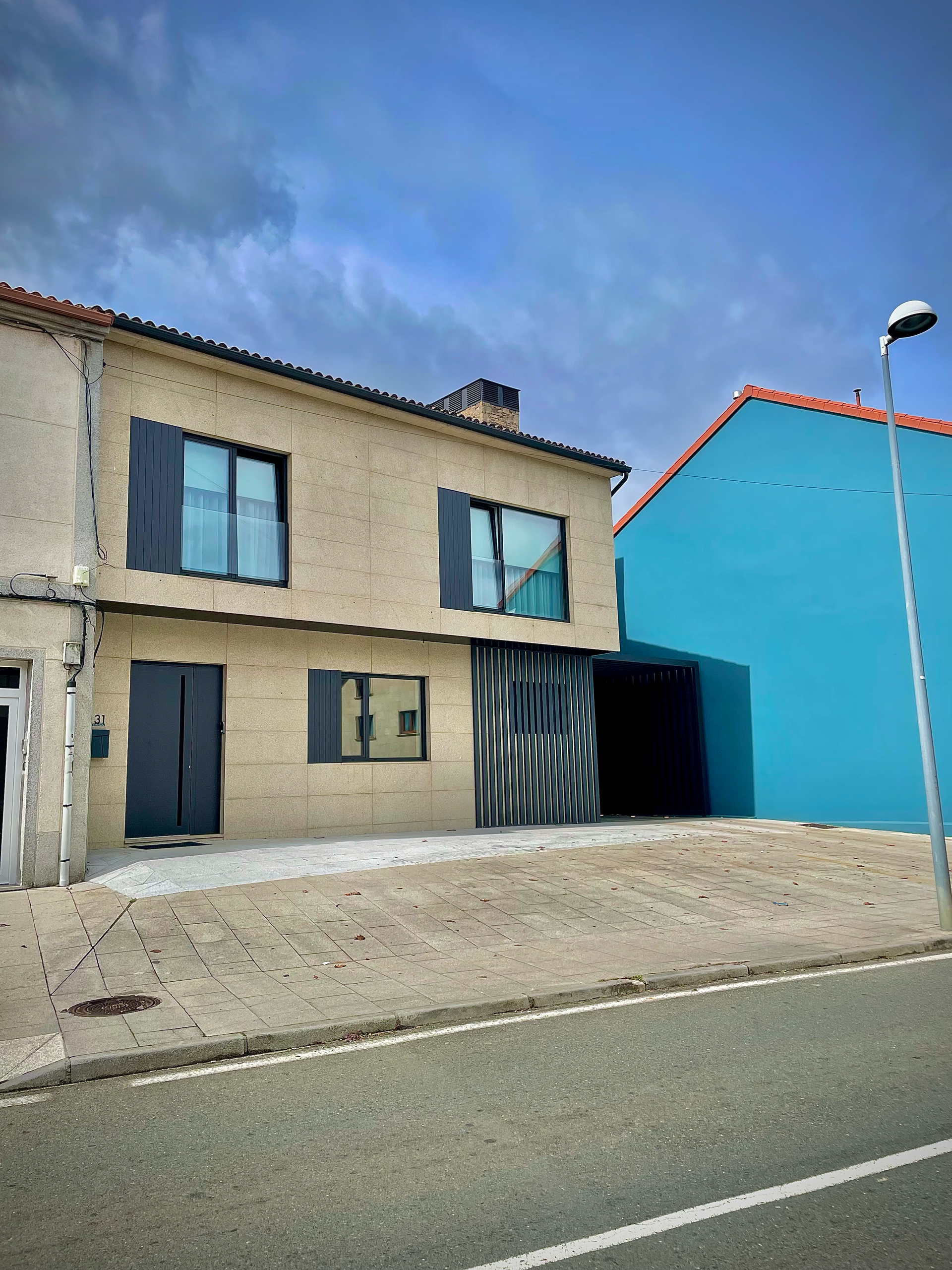 Una casa con una pared azul está al lado de una calle.