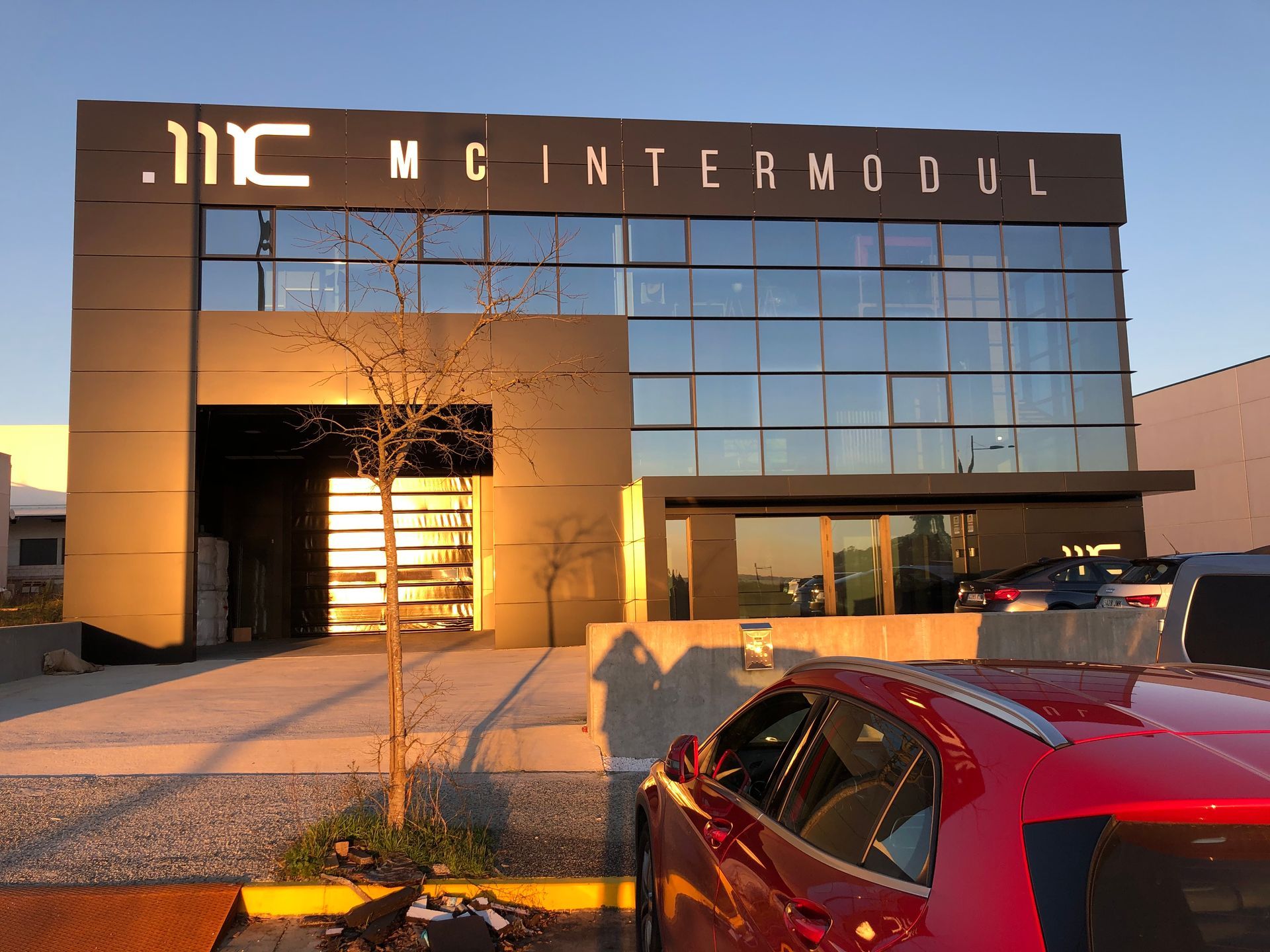 Un coche rojo está aparcado delante de un edificio que dice mc intermodul