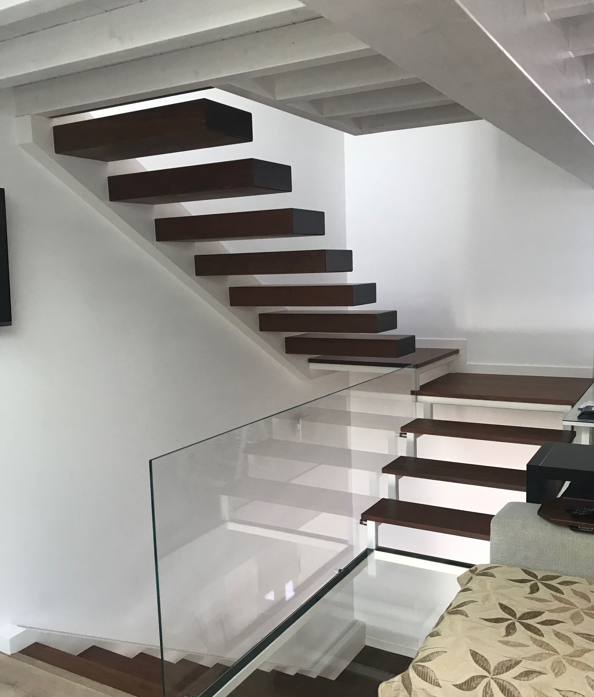 Una escalera con escalones de madera y barandilla de cristal.