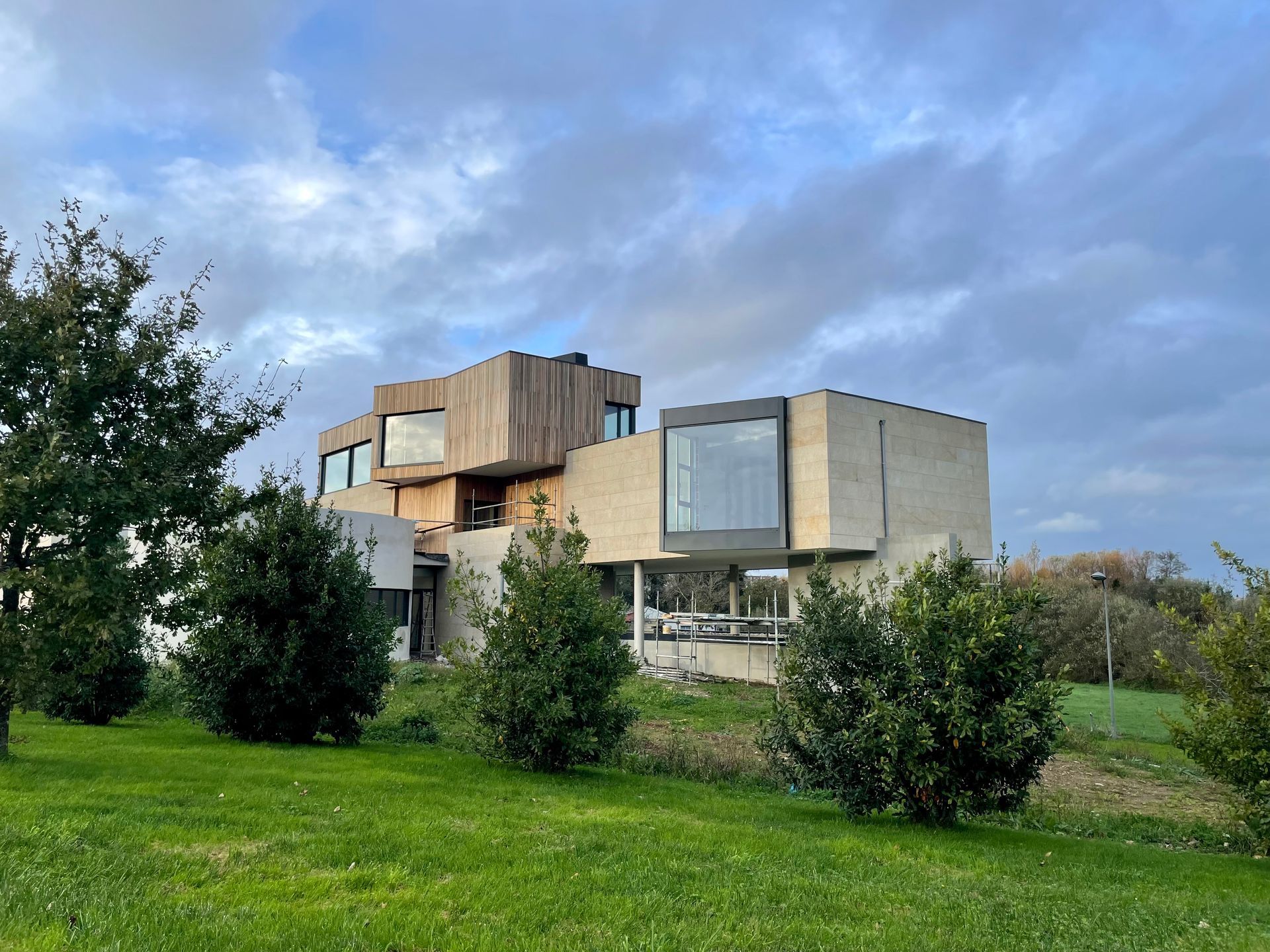 Una casa grande con muchas ventanas está rodeada de árboles y césped.