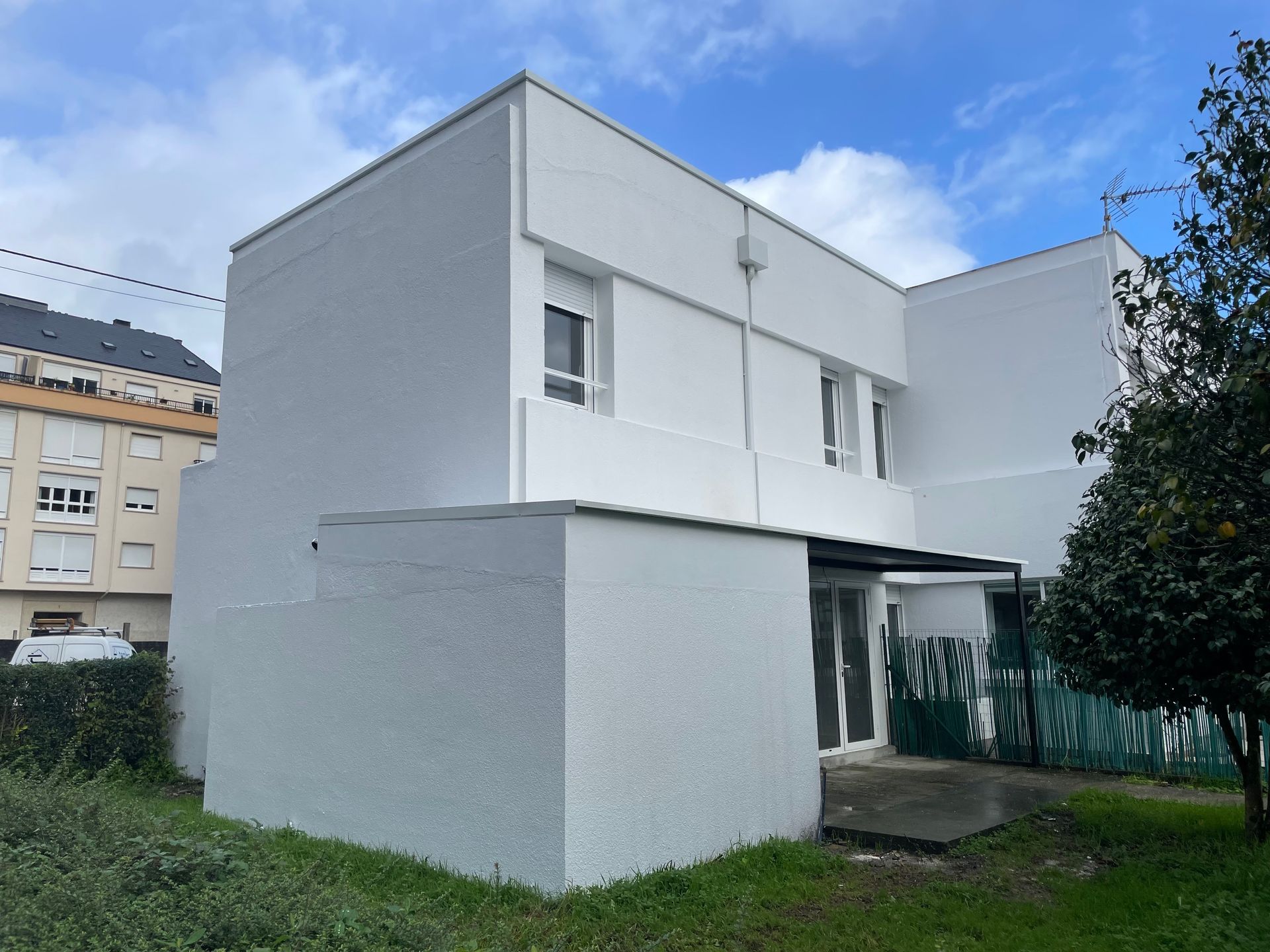 Un edificio blanco con un árbol delante.