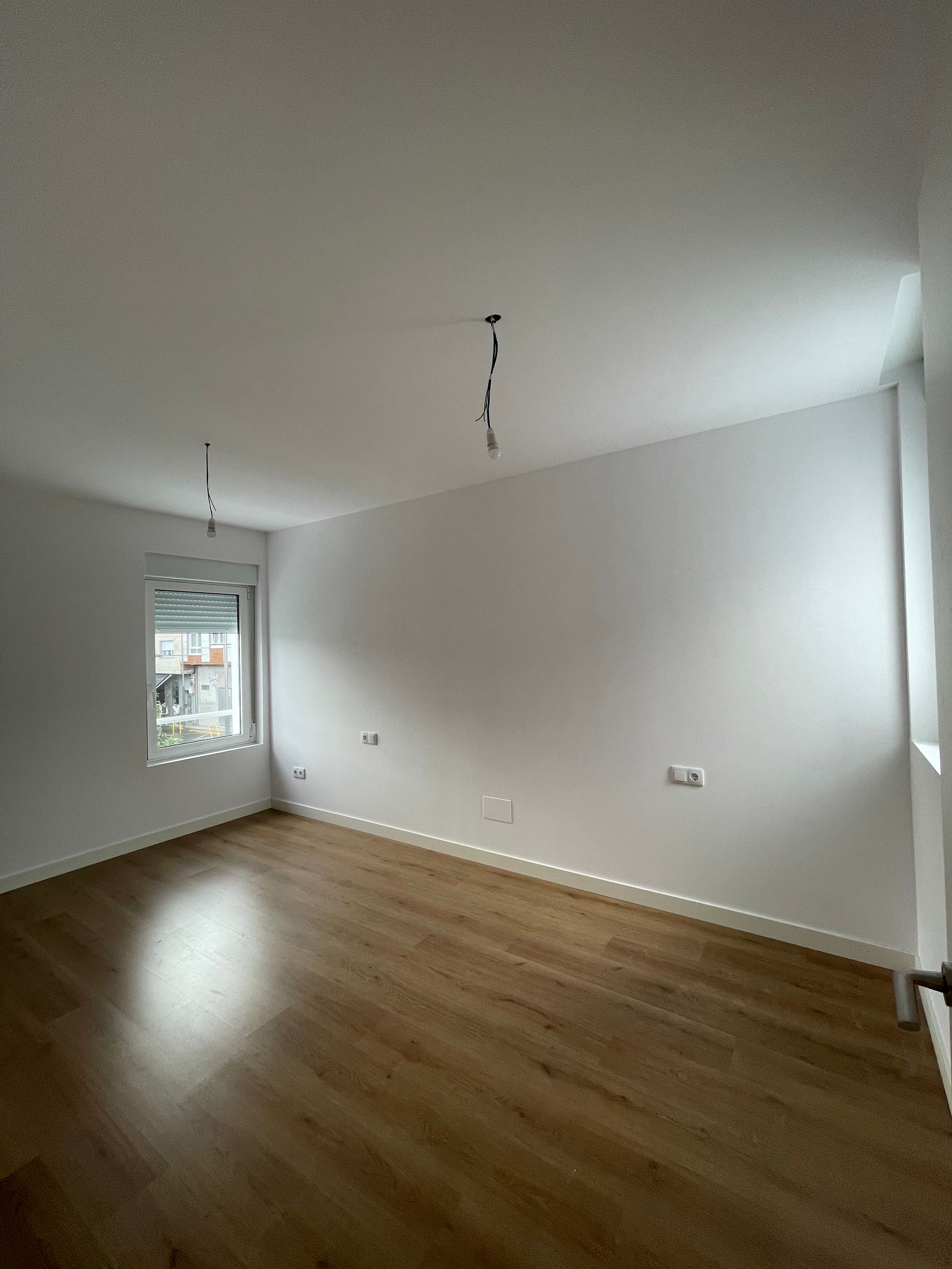 Una habitación vacía con pisos de madera y paredes blancas.