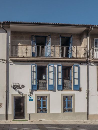 Un edificio blanco con ventanas azules y un balcón.