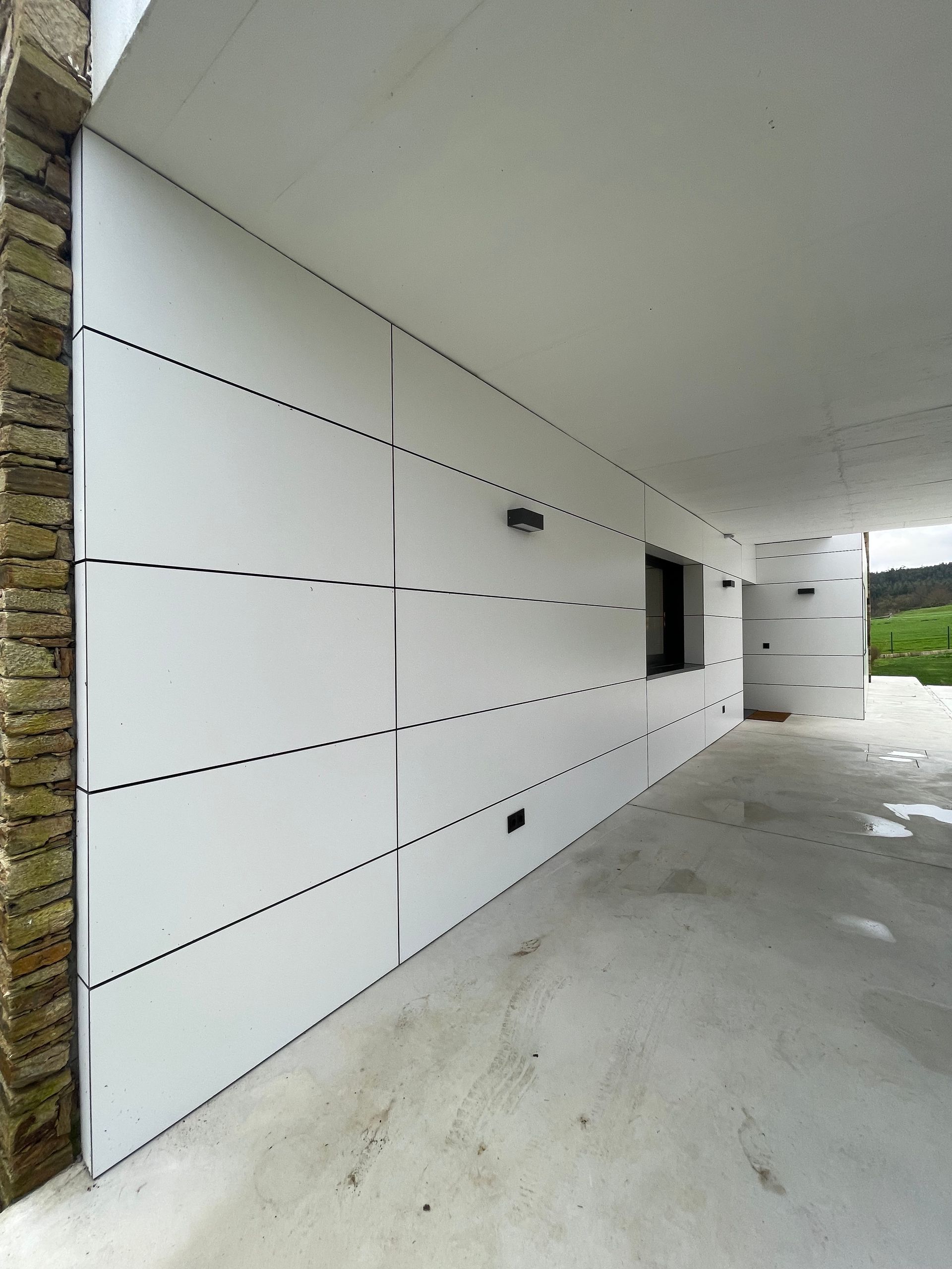 Una pared blanca con un muro de piedra detrás.