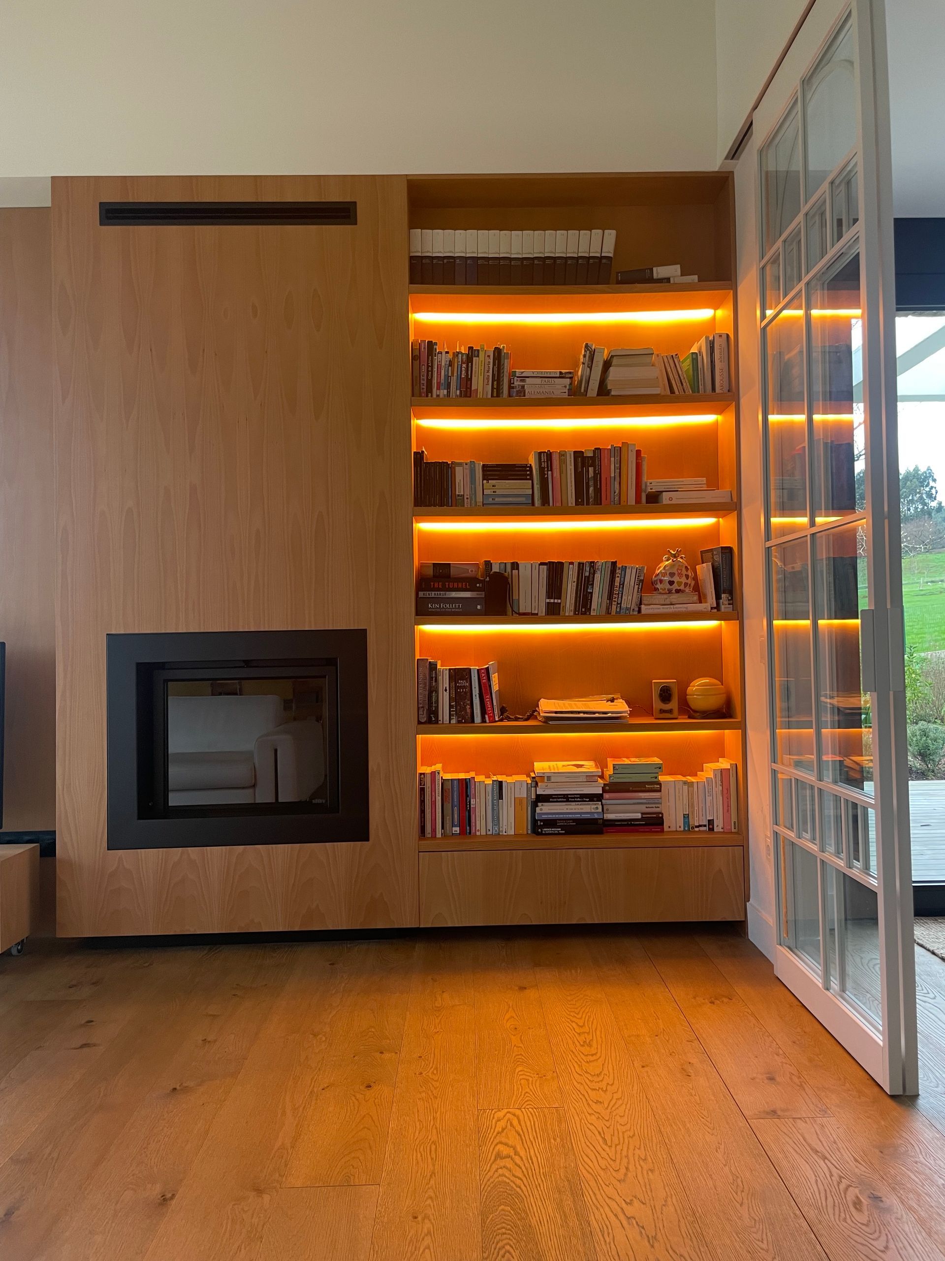 Una sala de estar con chimenea y estanterías llenas de libros.