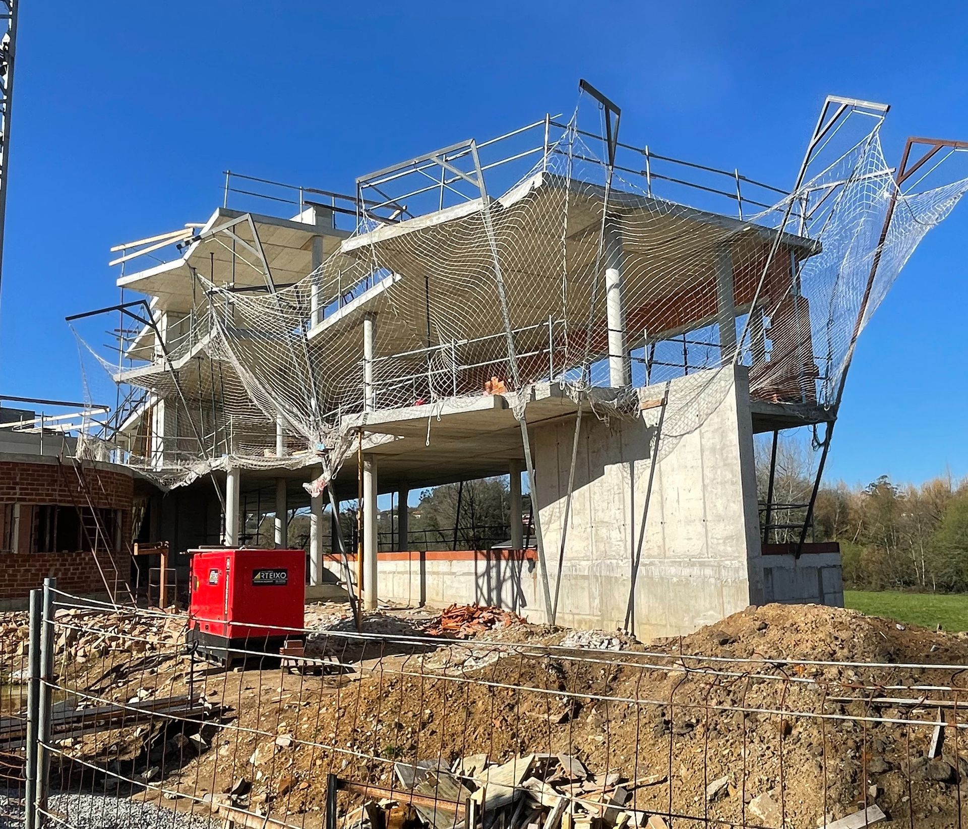 Un gran edificio en construcción con un camión rojo estacionado frente a él.