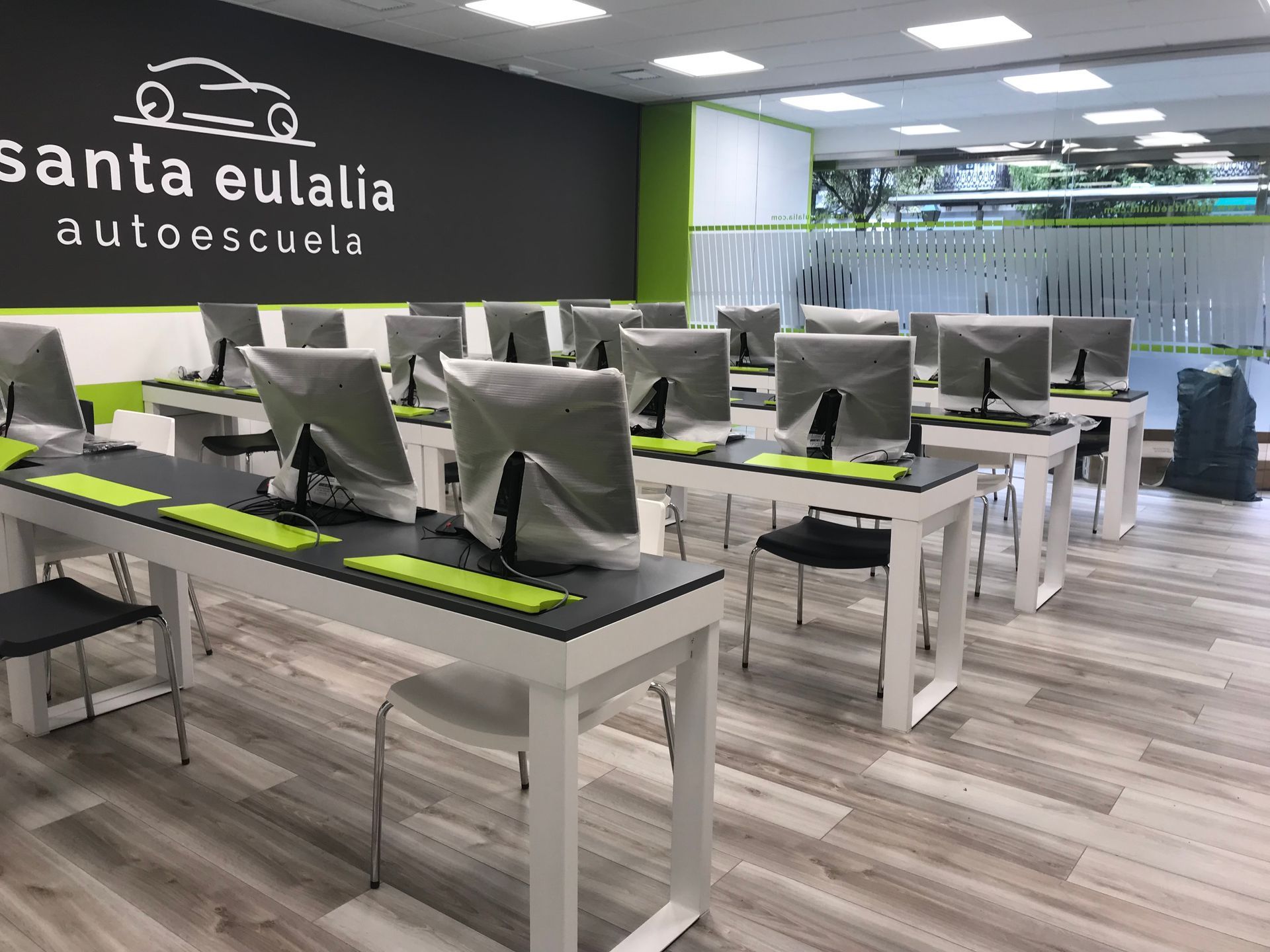 Un aula con mesas y sillas llenas de monitores de computadora.