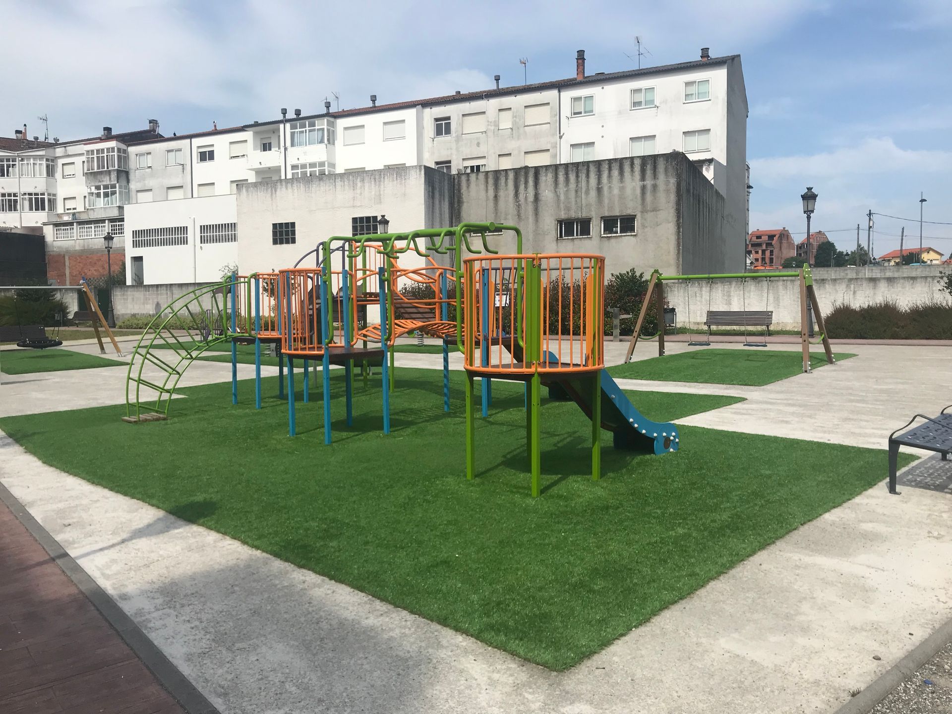 Un colorido patio de juegos en un parque con un edificio al fondo.
