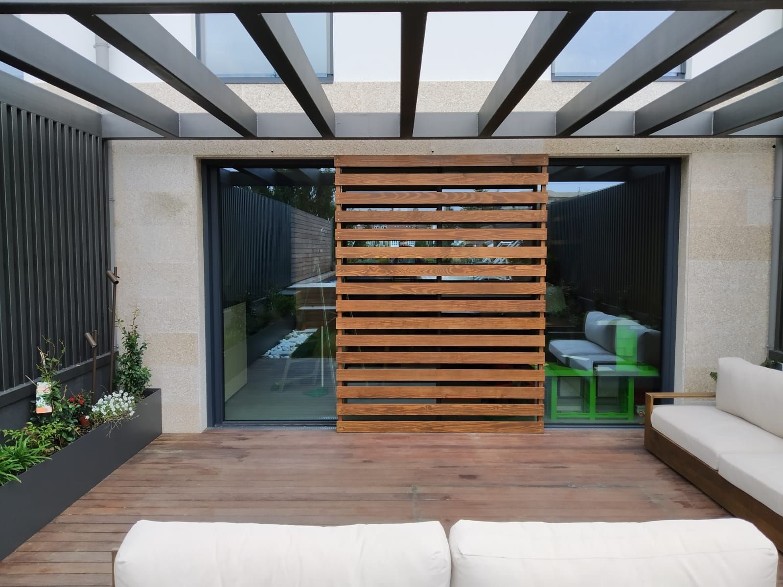 Un patio con una puerta corrediza de vidrio y una pared de madera.
