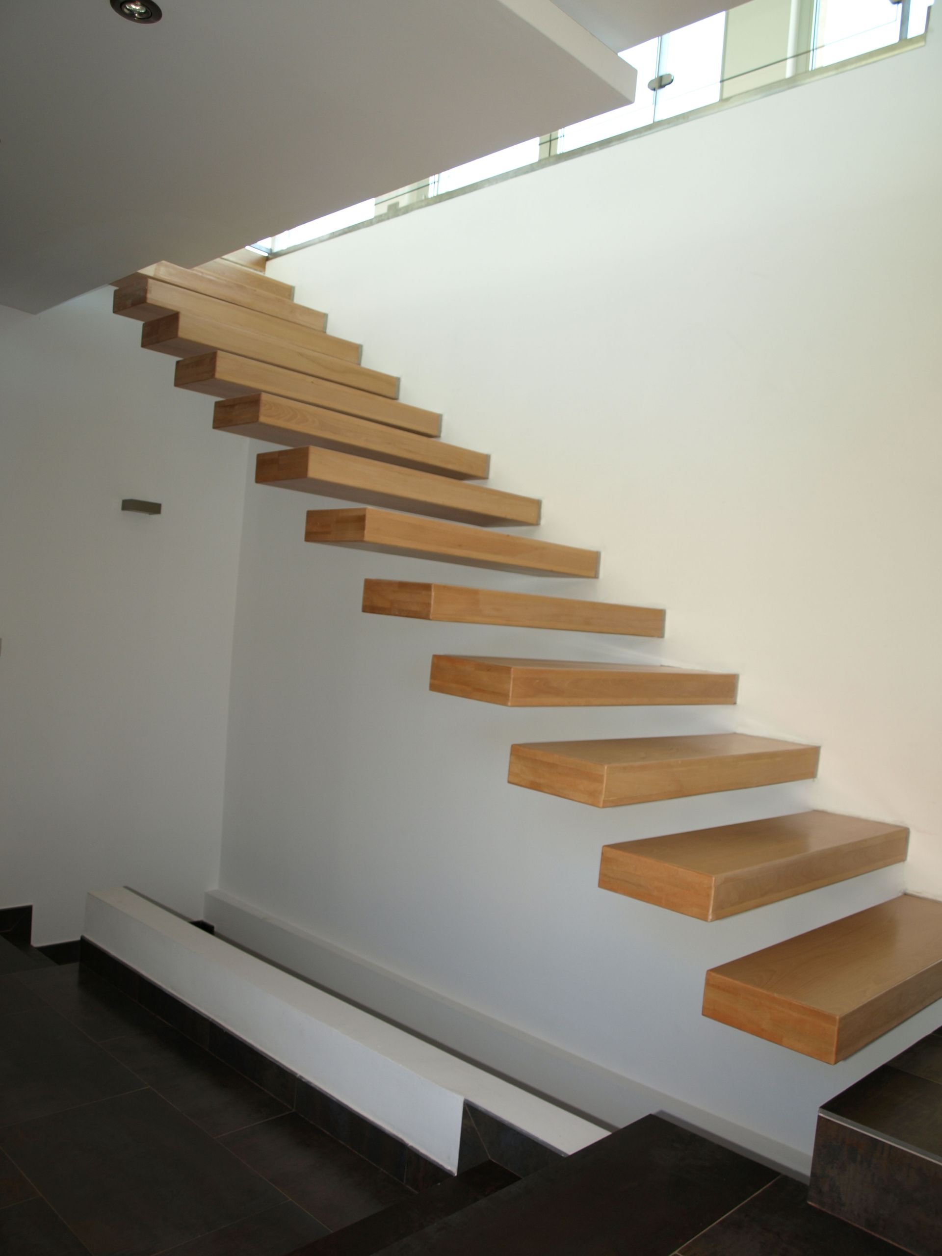 Una escalera de madera con una pared blanca detrás.