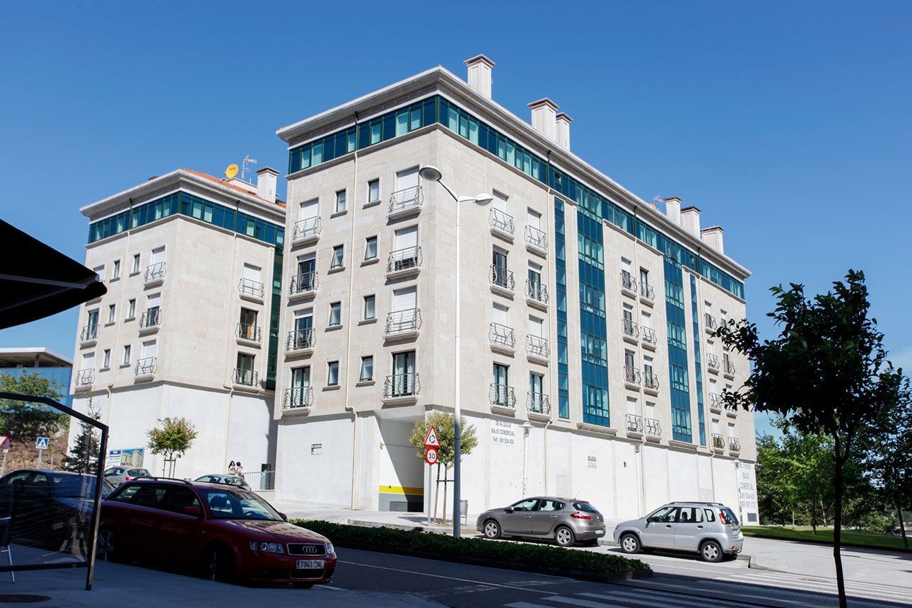 Un gran edificio con coches aparcados delante.