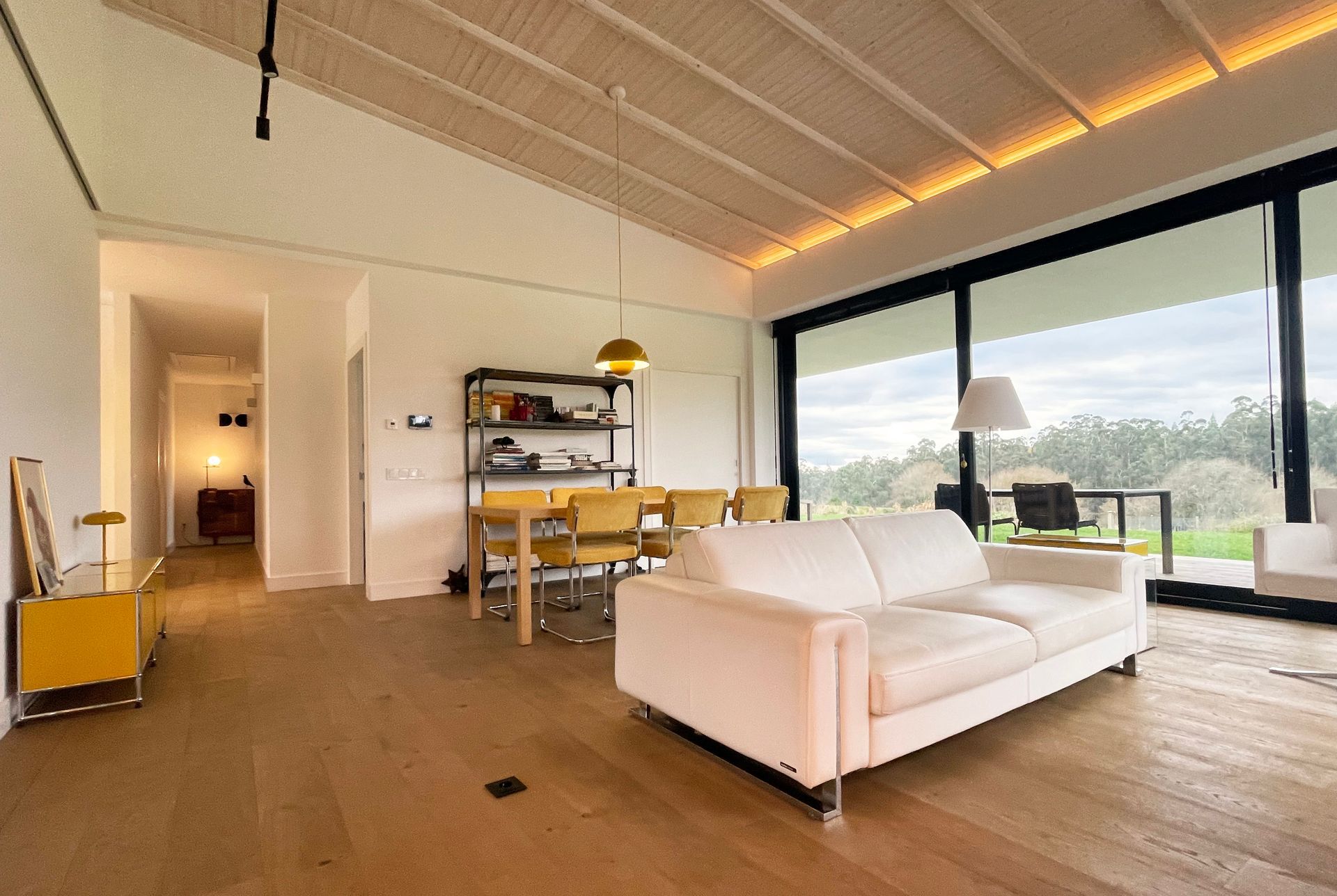Una sala de estar con un sofá blanco y un comedor al fondo.