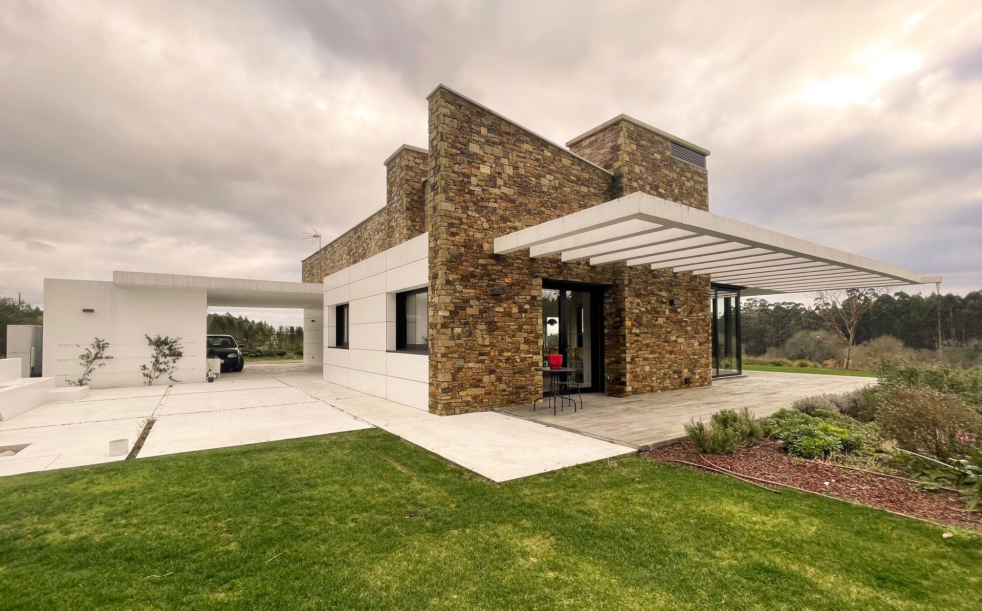 Una casa de piedra moderna con una pérgola delante.