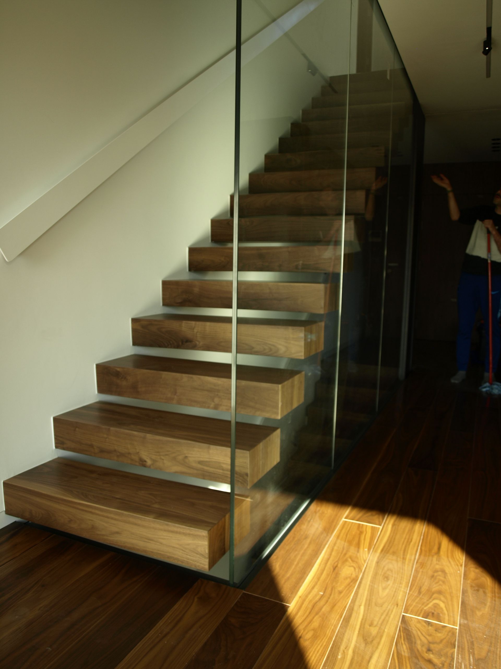 Una escalera con escalones de madera y barandilla de cristal.