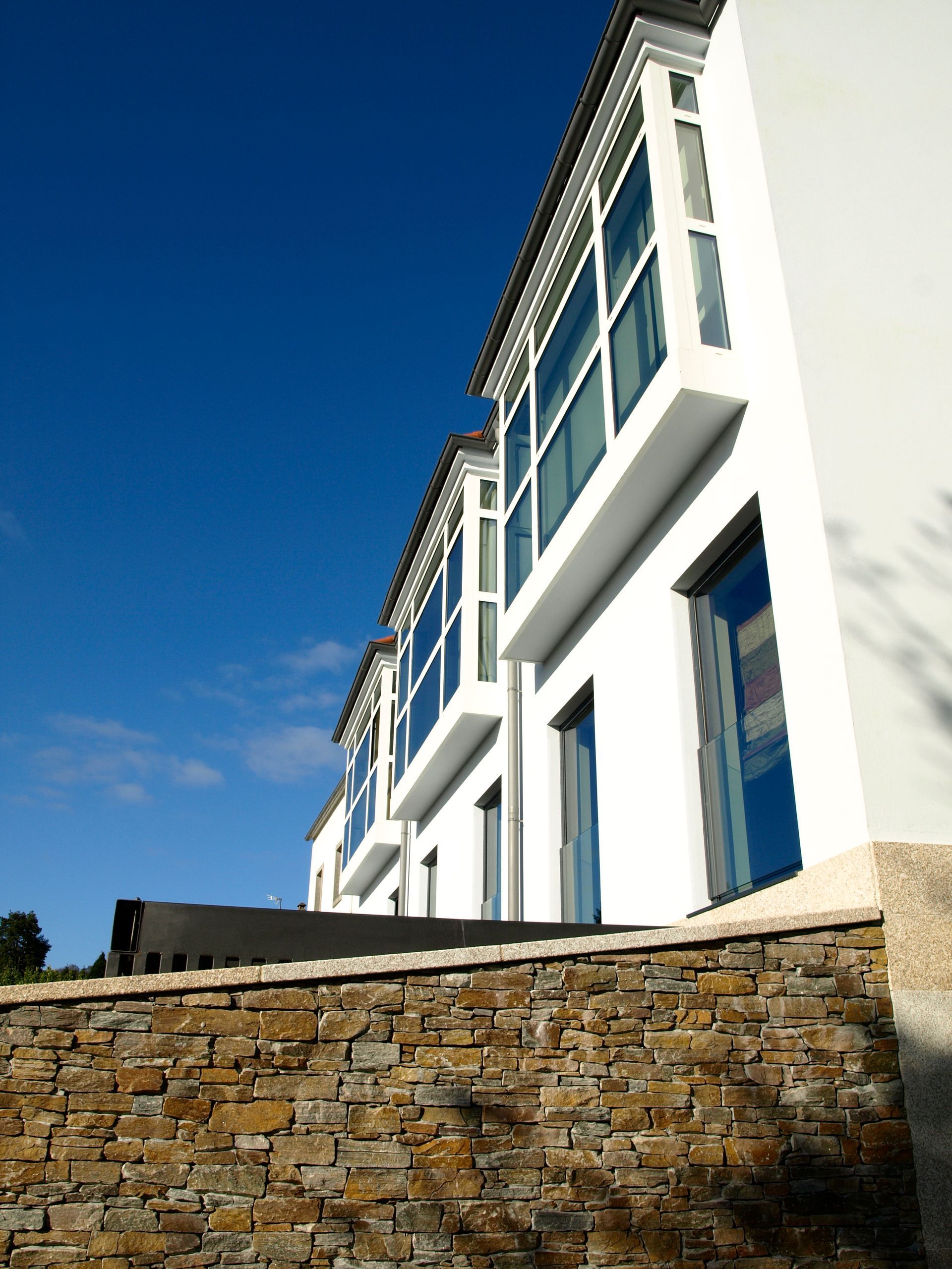 Un edificio blanco con un muro de piedra delante.