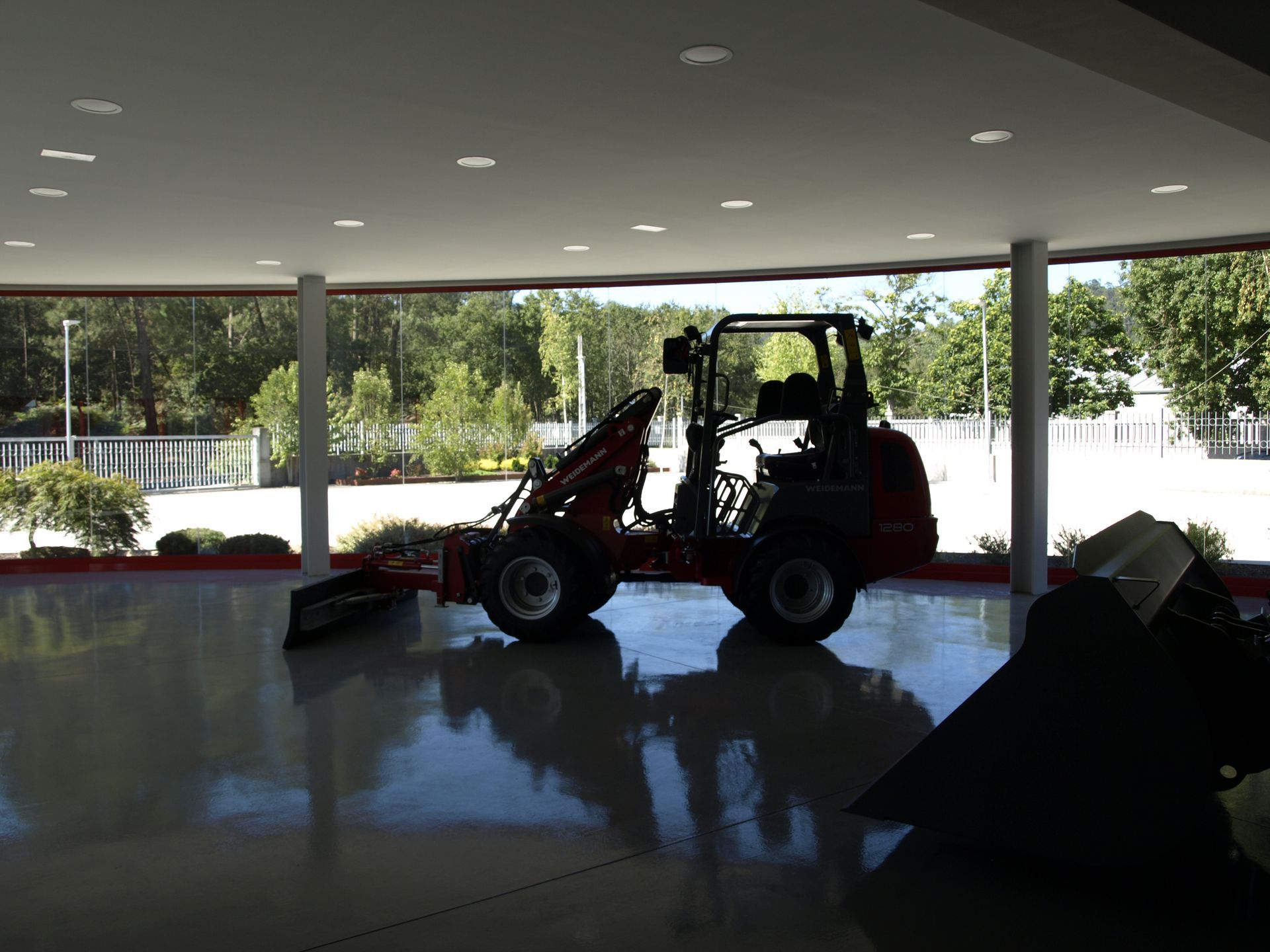 Un tractor está estacionado en una habitación con muchas ventanas.