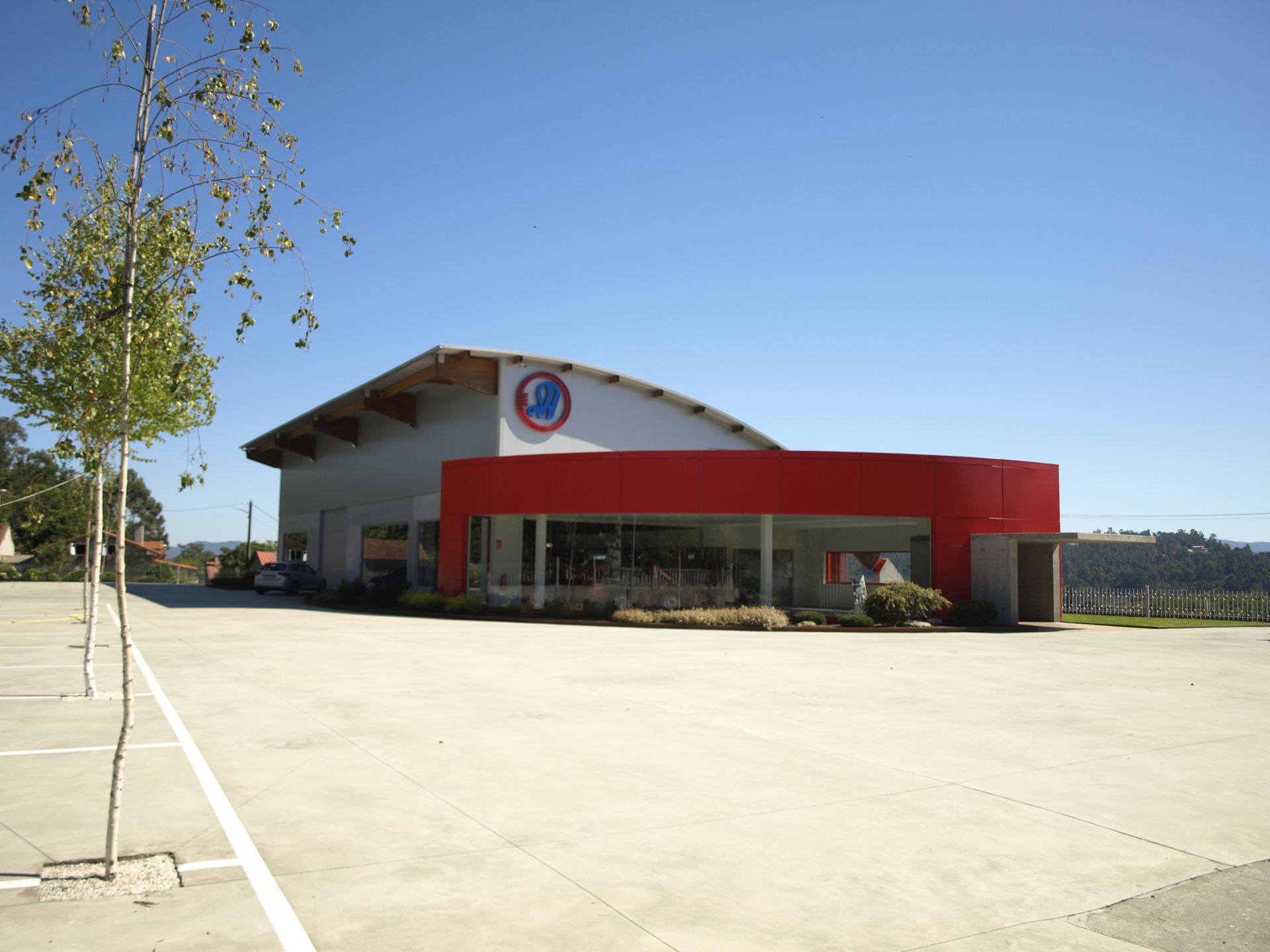 Un edificio rojo y blanco con un estacionamiento enfrente.