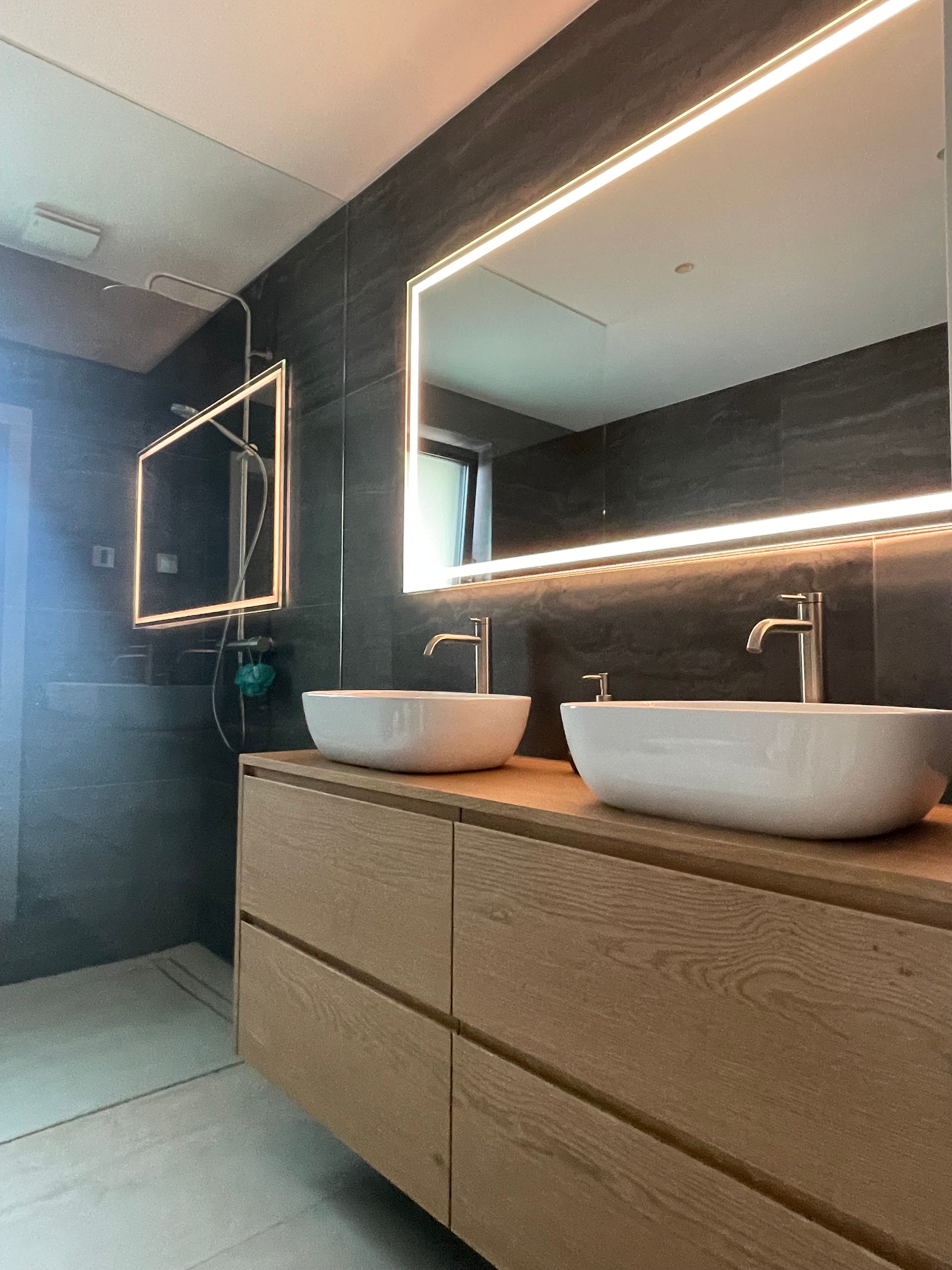 Un baño con dos lavabos y un espejo grande.