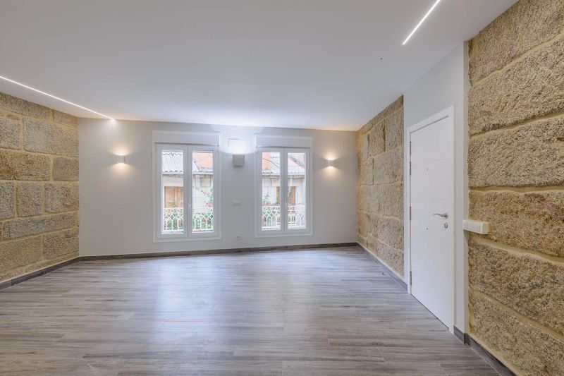 Una sala de estar vacía con suelo de madera y una pared de piedra.