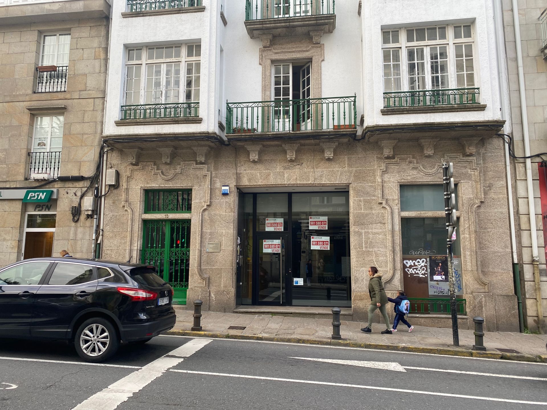 Un coche negro está aparcado delante de un edificio.