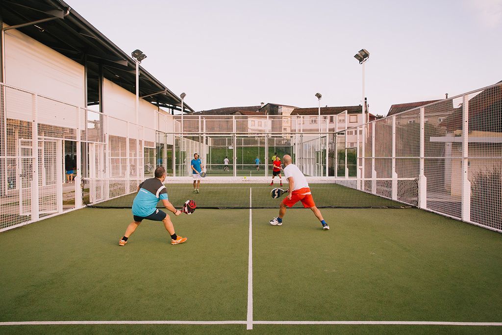 Dos hombres están jugando al pádel en una cancha.