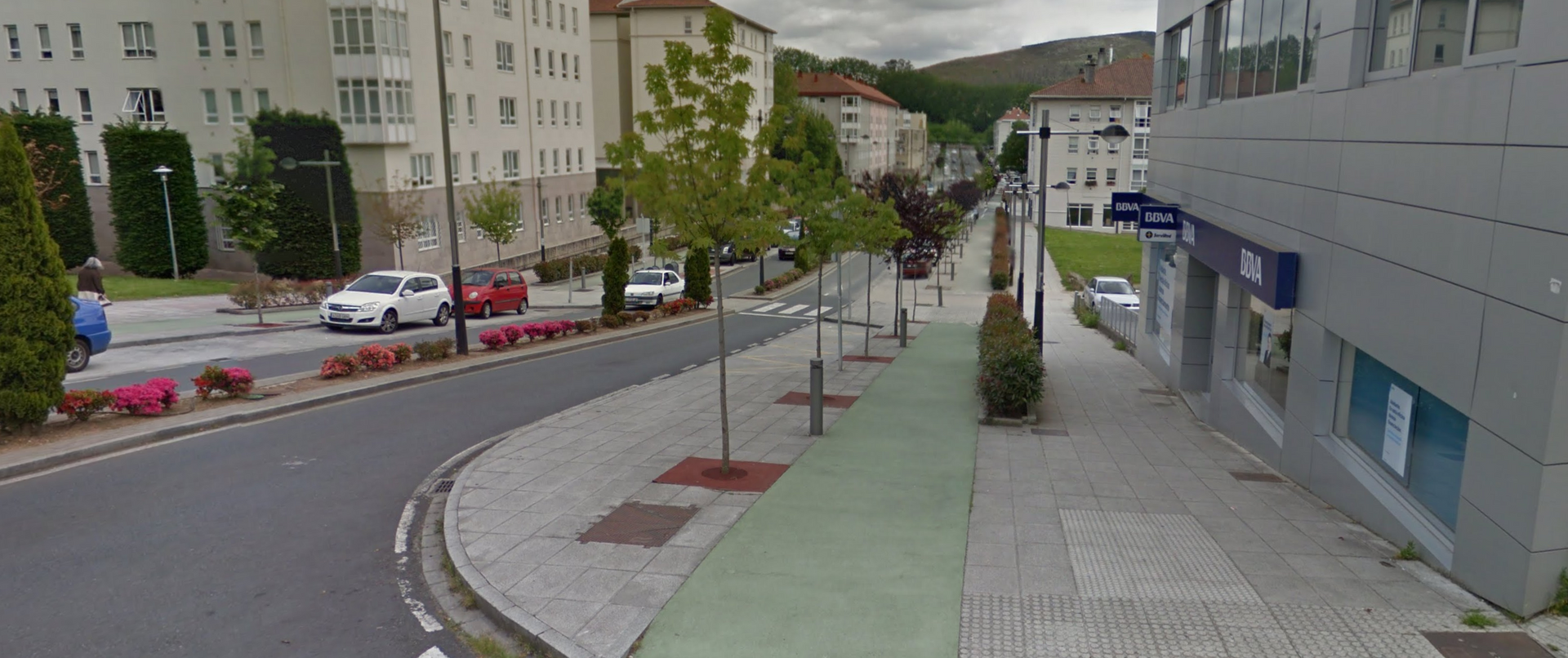 Una calle con coches circulando por ella y una acera.